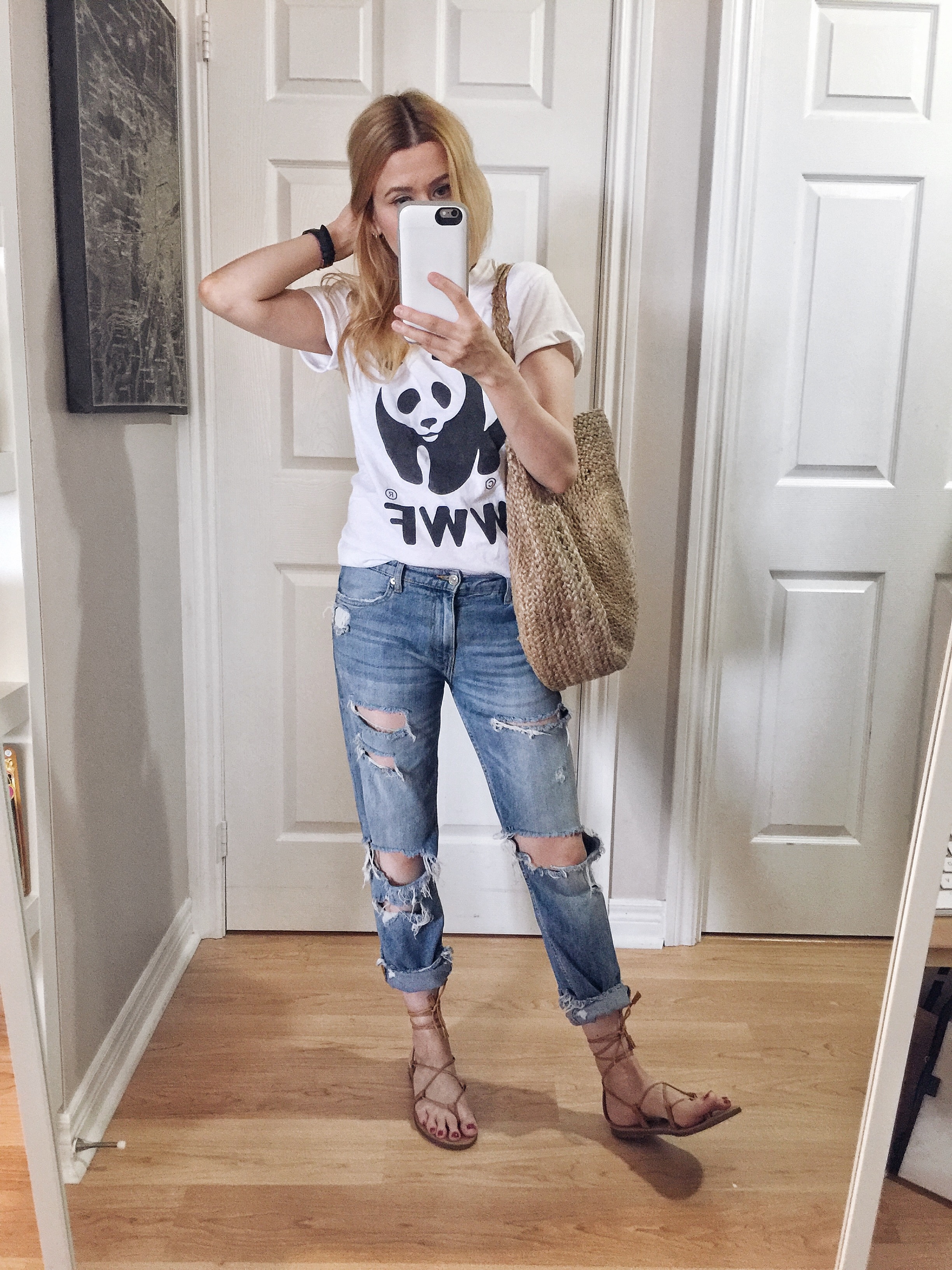 I am wearing a World Wildlife Fund T-shirt, boyfriend jeans, a large woven circle purse, and Madewell Boardwalk Sandals.