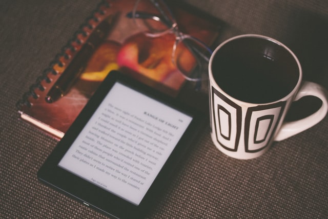 Coffee, glasses, and ereader on table.