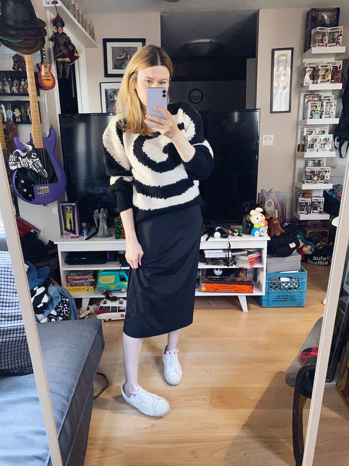 A Woman is wearing a black slip dress with a Paloma Wool Sweater over the top, and white Golden Goose Sneakers.