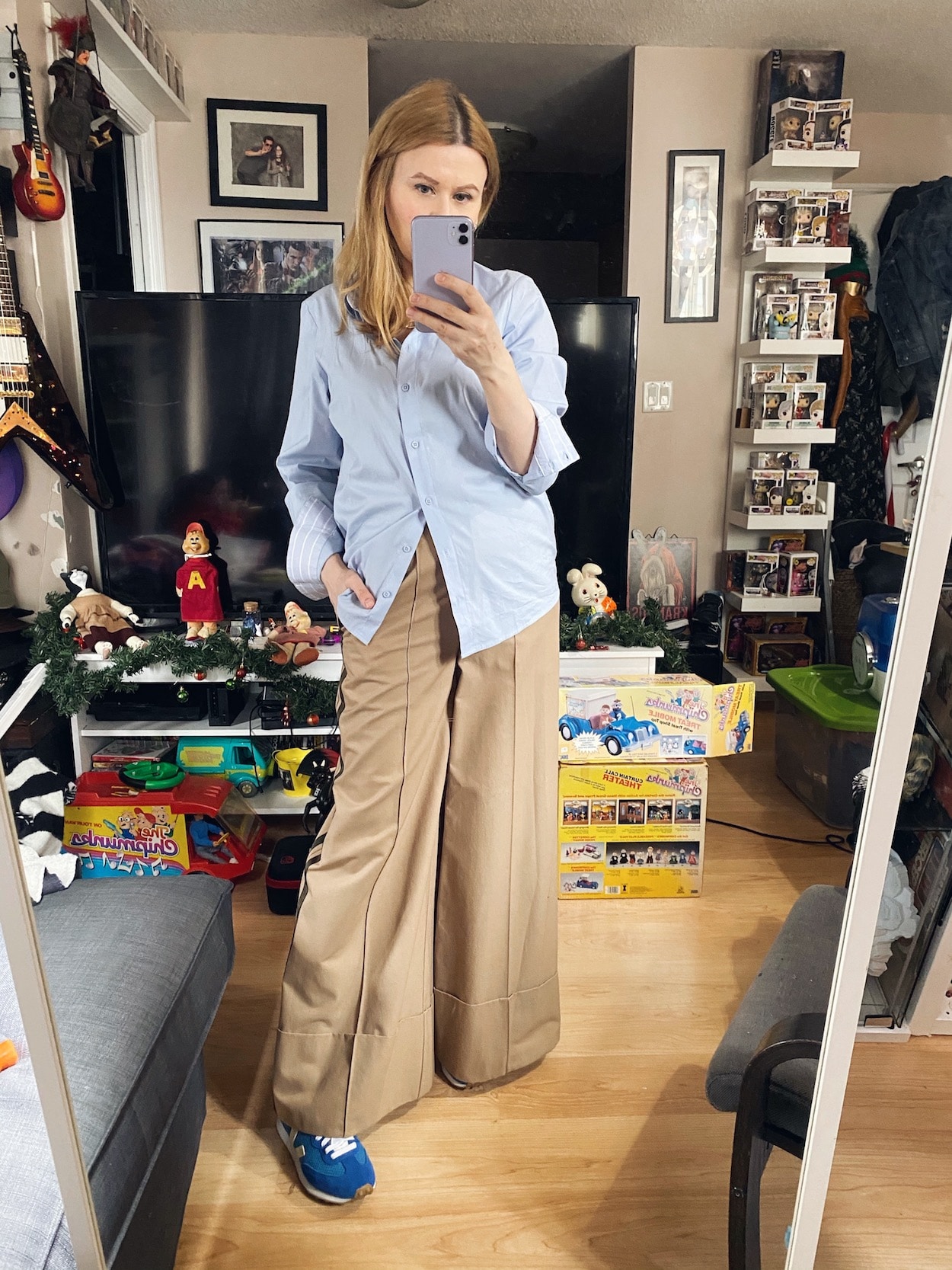 A woman is wearing an oversized blue button, and wide leg trousers