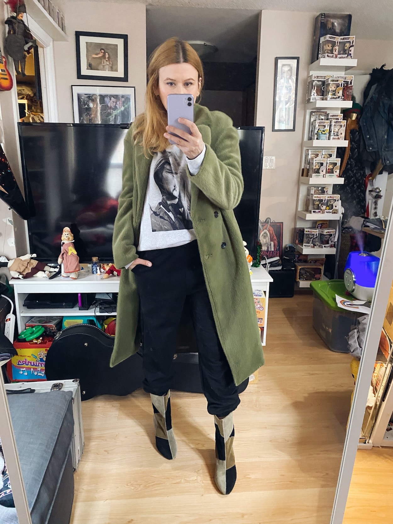 A woman is wearing an anine bing sweatshirt, joggers, and a green coat