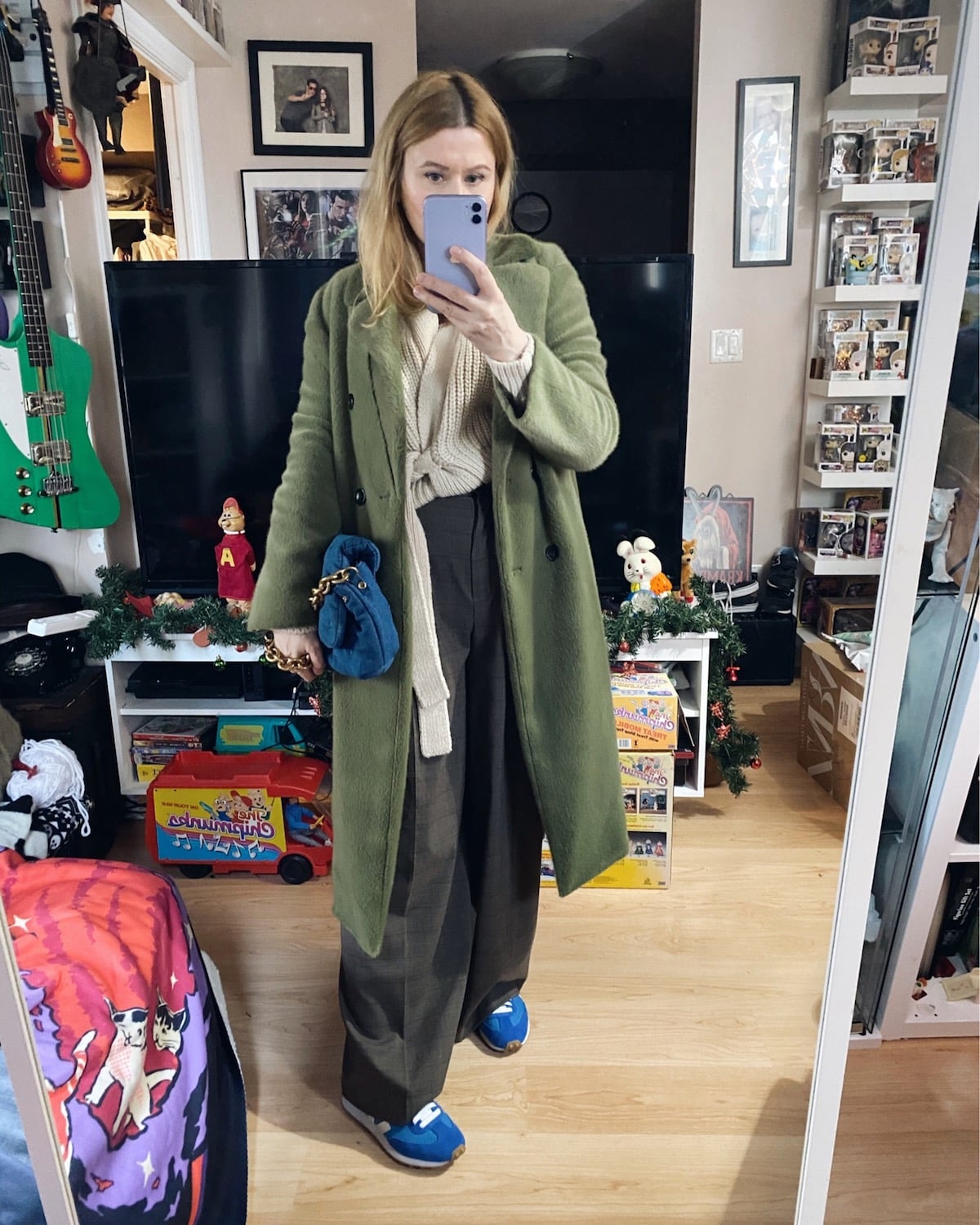 A woman wearing a green faux fur coat, sweater, and wide leg trousers