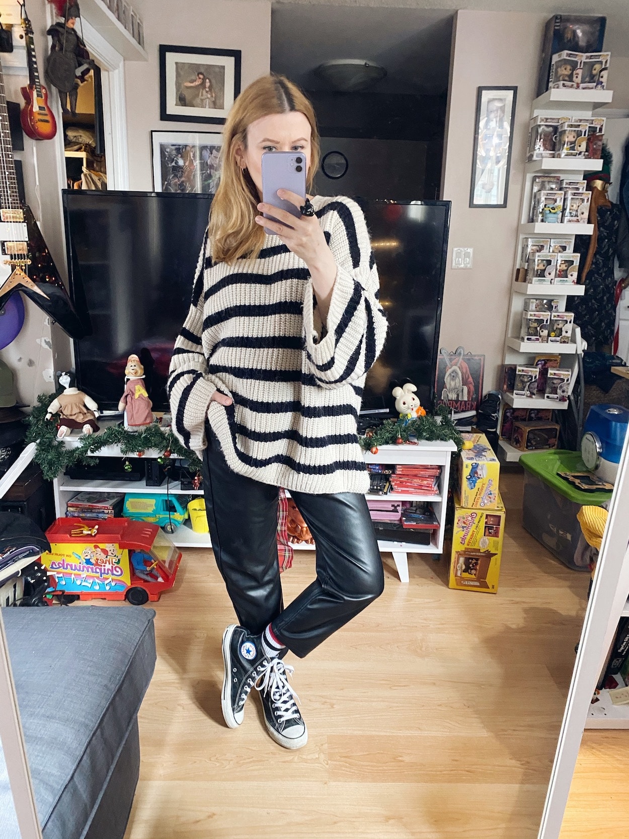 a Woman is wearing an oversized striped sweater, and faux leather trousers