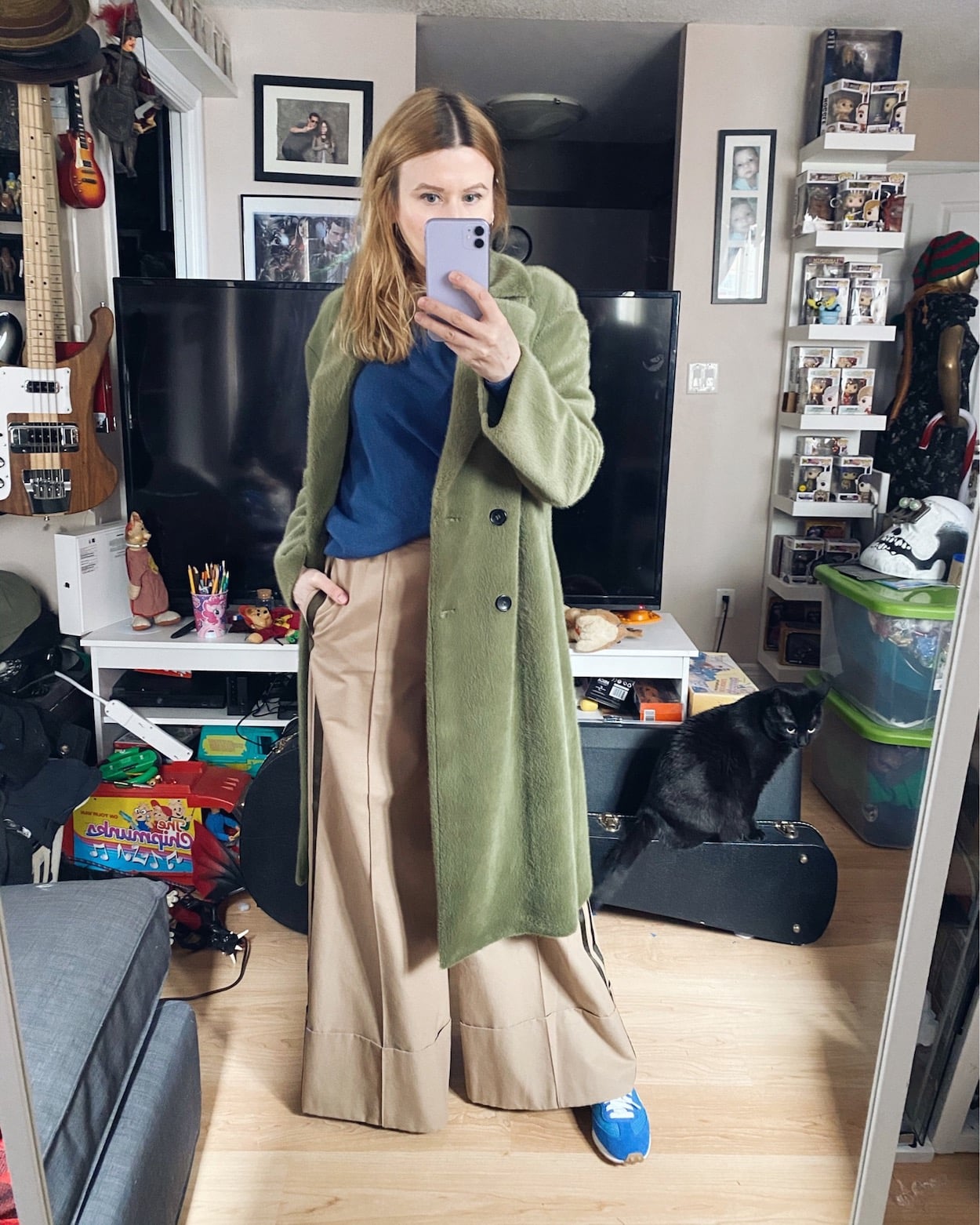 I am wearing a blue cashmere sweater, wide leg trousers, a green faux fur coat, and blue Veja sneakers.