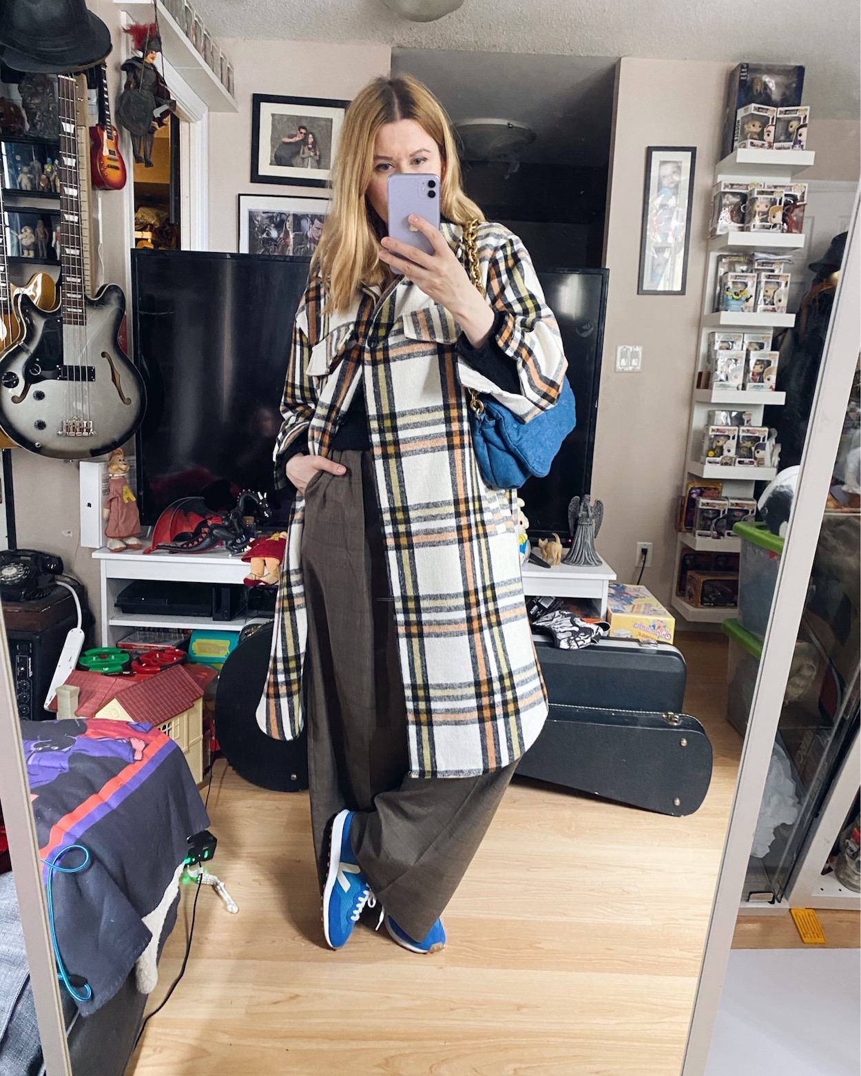 I am wearing wide leg trousers, a black wrap sweater, a plaid shacket, and blue sneakers