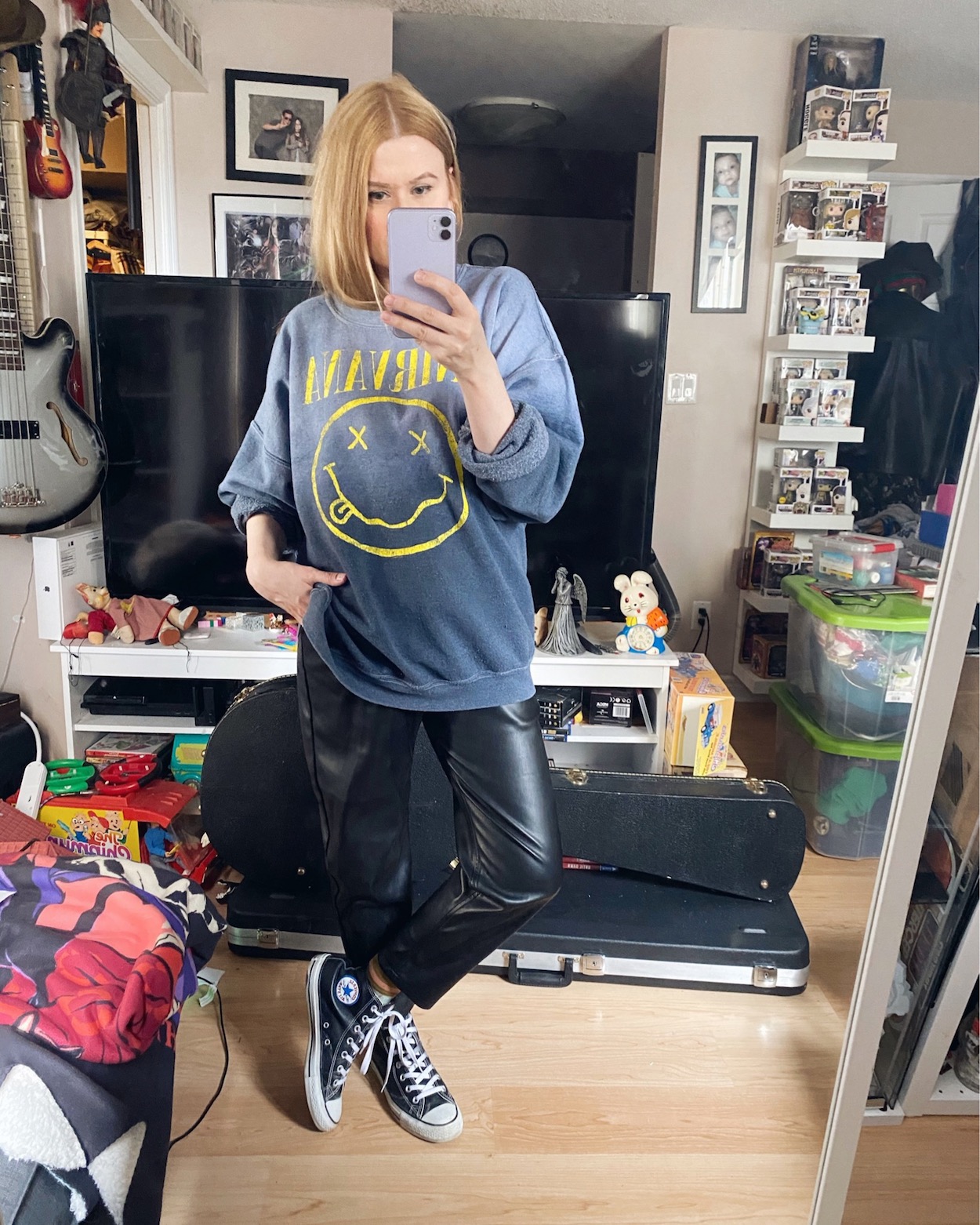 I am wearing an oversized Nirvana sweatshirt, faux leather trousers, and Converse