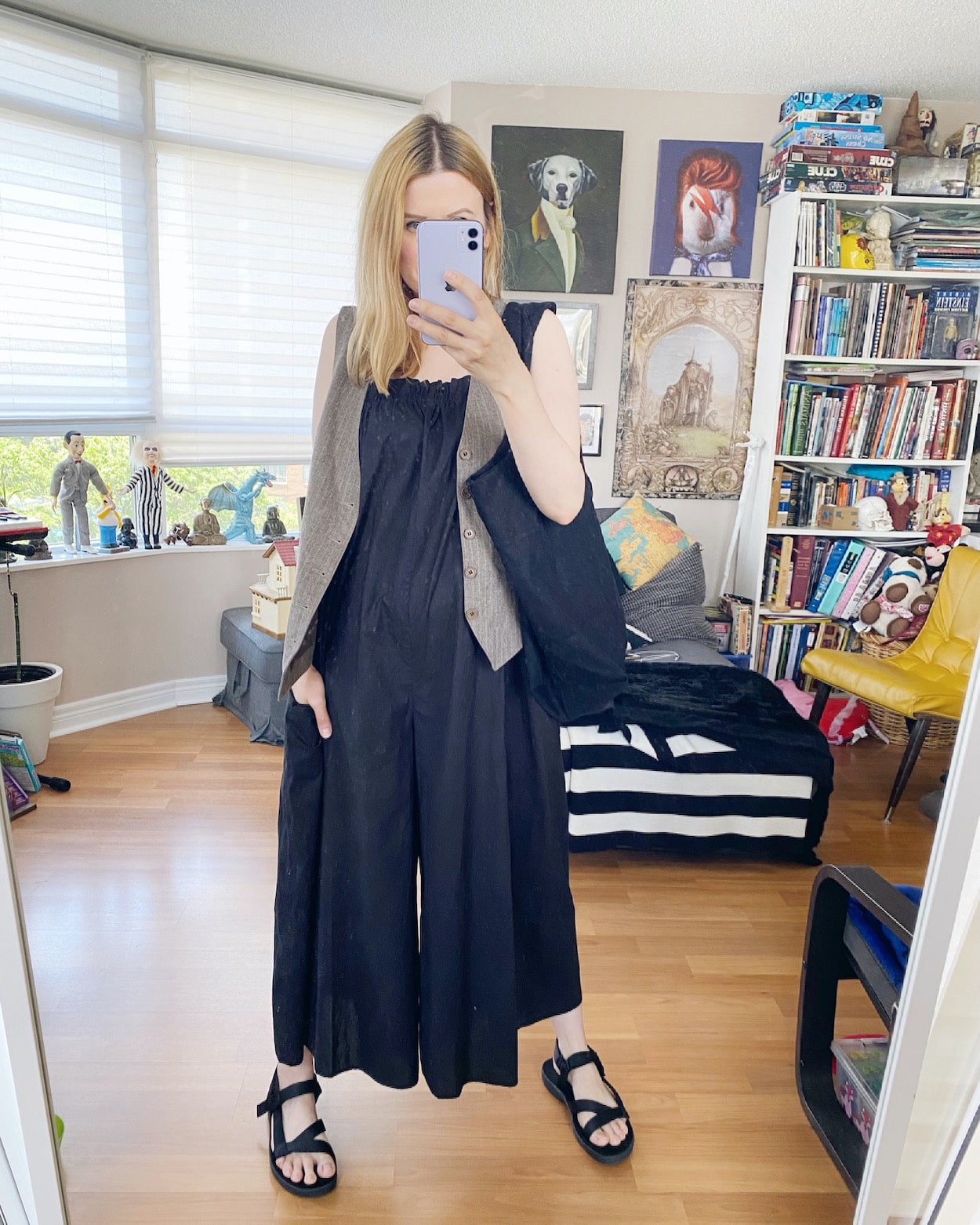 I am wearing a black jumsuit, vest, dad sandals, and a black tote.