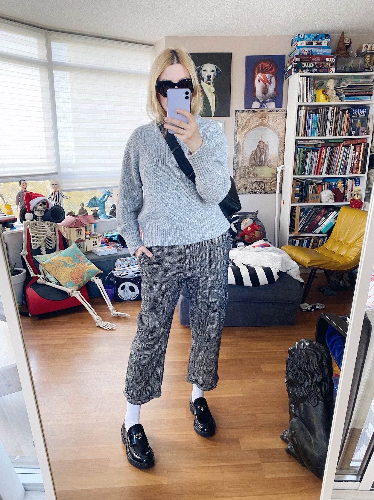 I am wearing a grey sweater, vintage trousers, black sunnies, Prada loafers, and a crossbody.