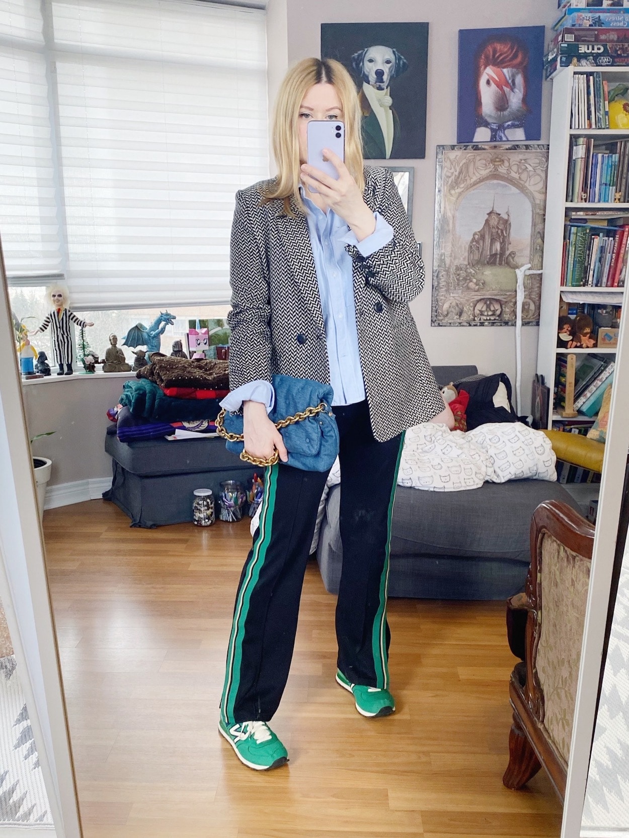 A blonde woman is wearing a blue button up, track pants, a houndstooth blazer, green sneakers, and a Zara bag.