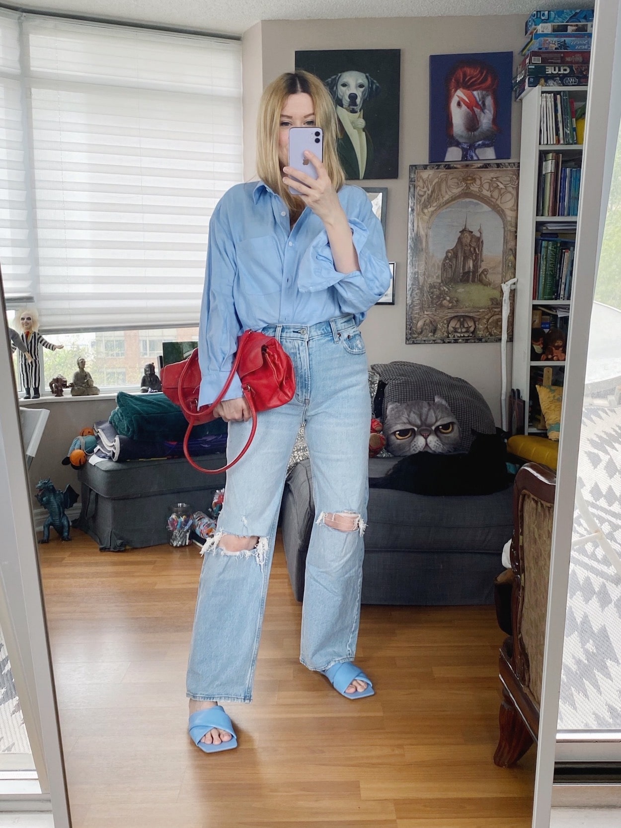 A blonde woman is wearing a cropped linen button up, Abercrombie 90s jeans, blue sandals, and a vintage Prada bag.