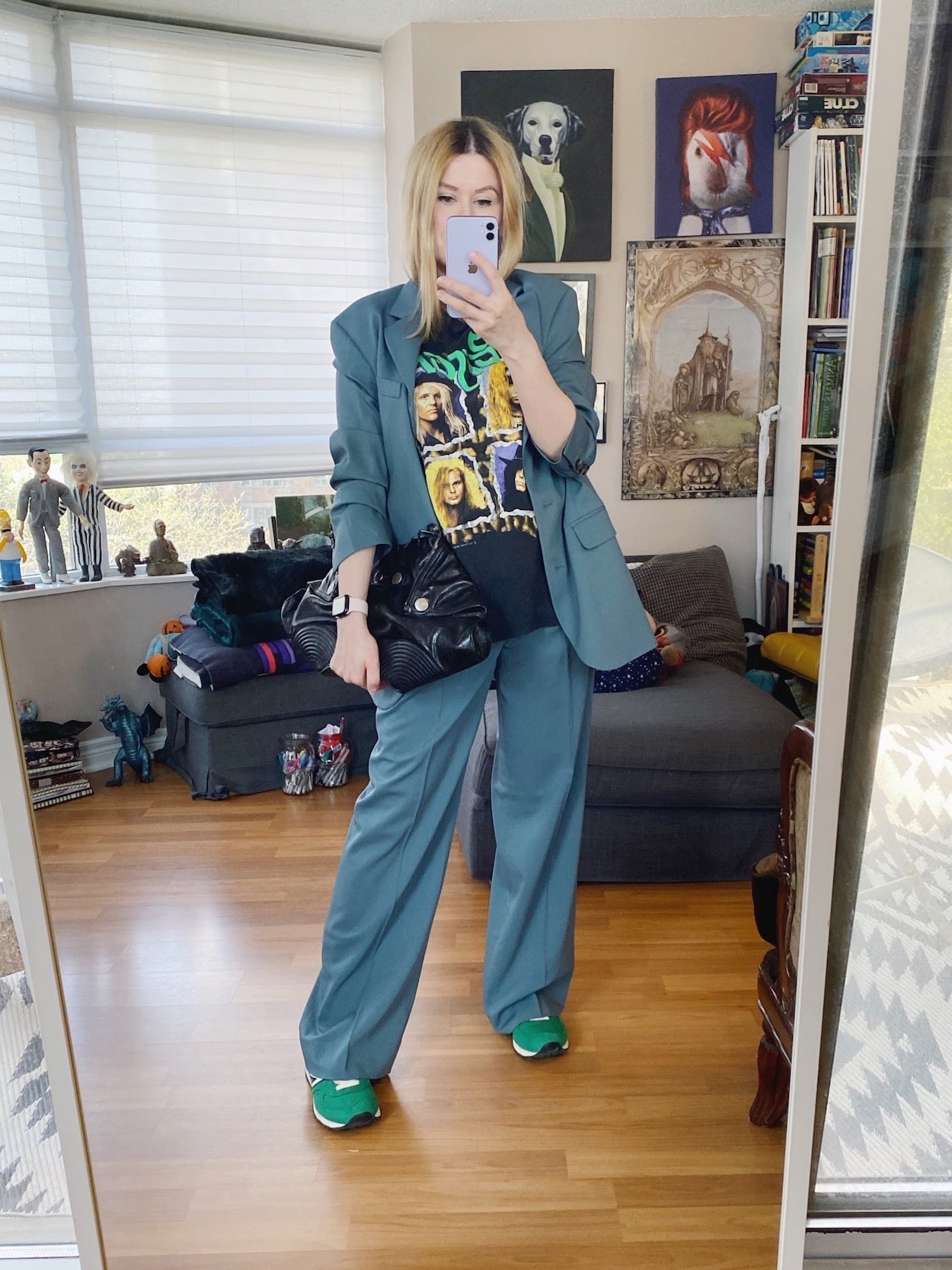 A blonde woman is wearing a matching blue wool suit, a vintage Poison tee, green sneakers, and an Alexander McQueen bag.