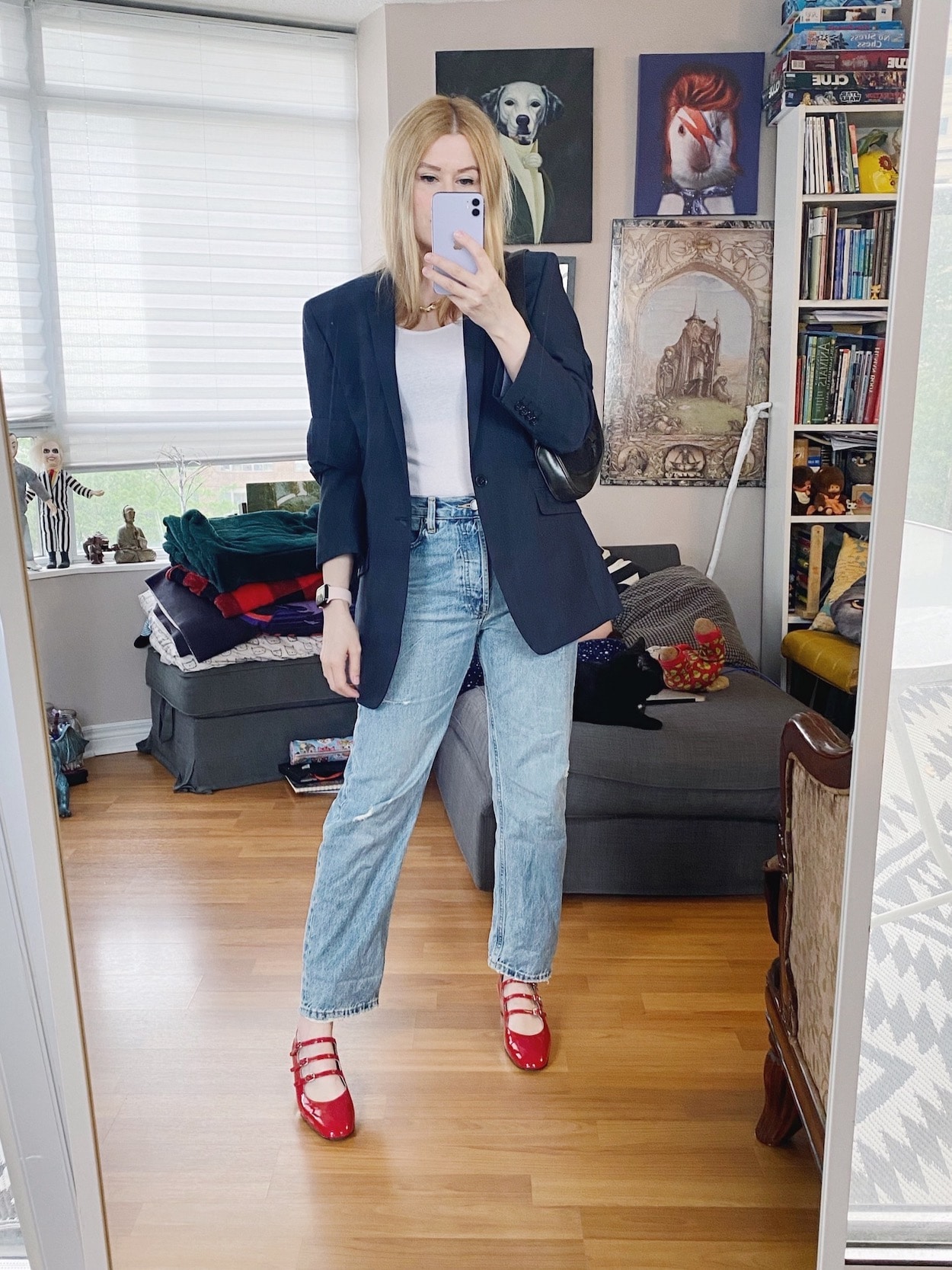 A blonde woman is wearing a white tank top, everlane jeans, a men's blazer, Carel Kina shoes, and a vintage Gucci bag.