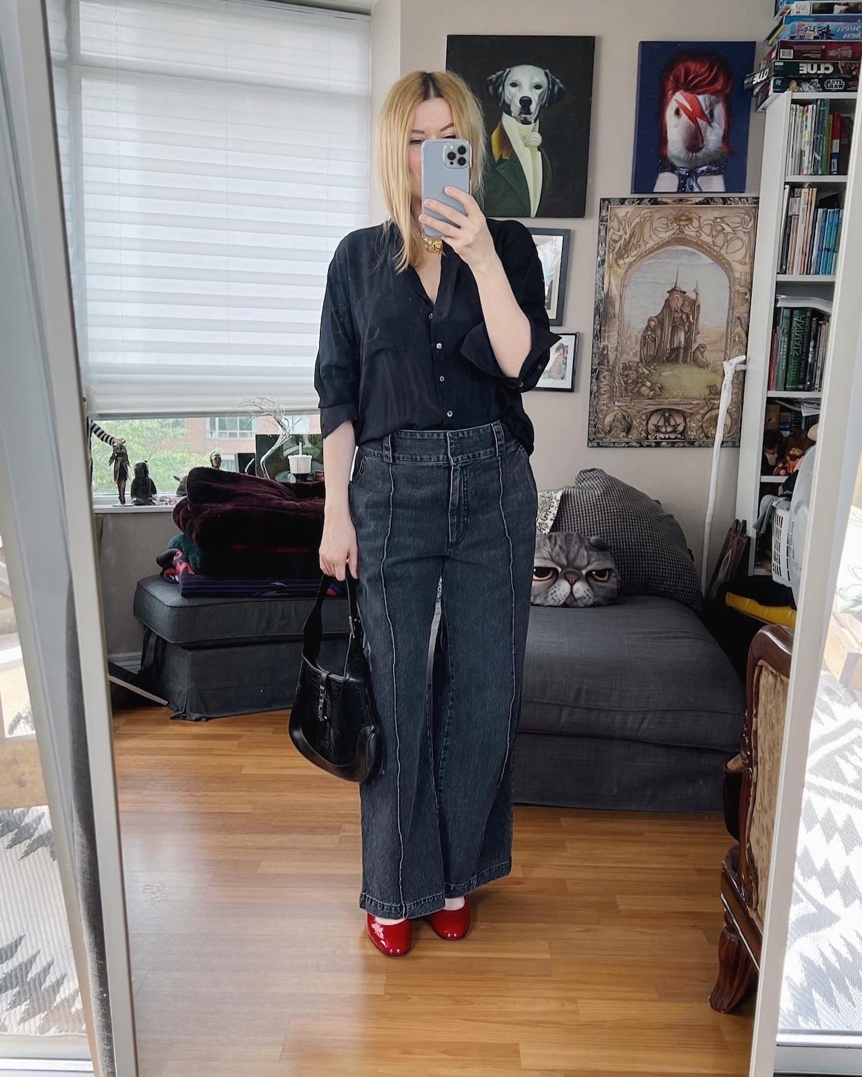 A blonde woman is wearing wide leg jeans, a silk blouse, a vintage necklace, Vintage Gucci bag, and red Carels.