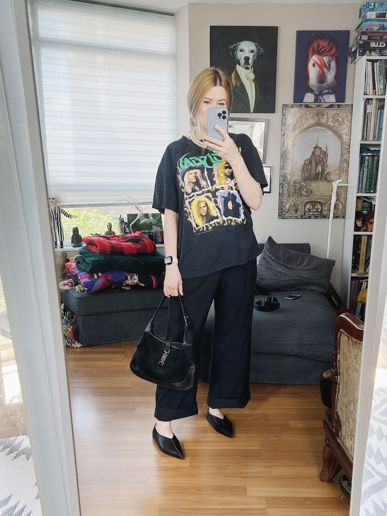 a blonde woman is wearing black trousers, a vintage Poison t-shirt, pointy toe flats, a vintage necklace, and a vintage Gucci bag.