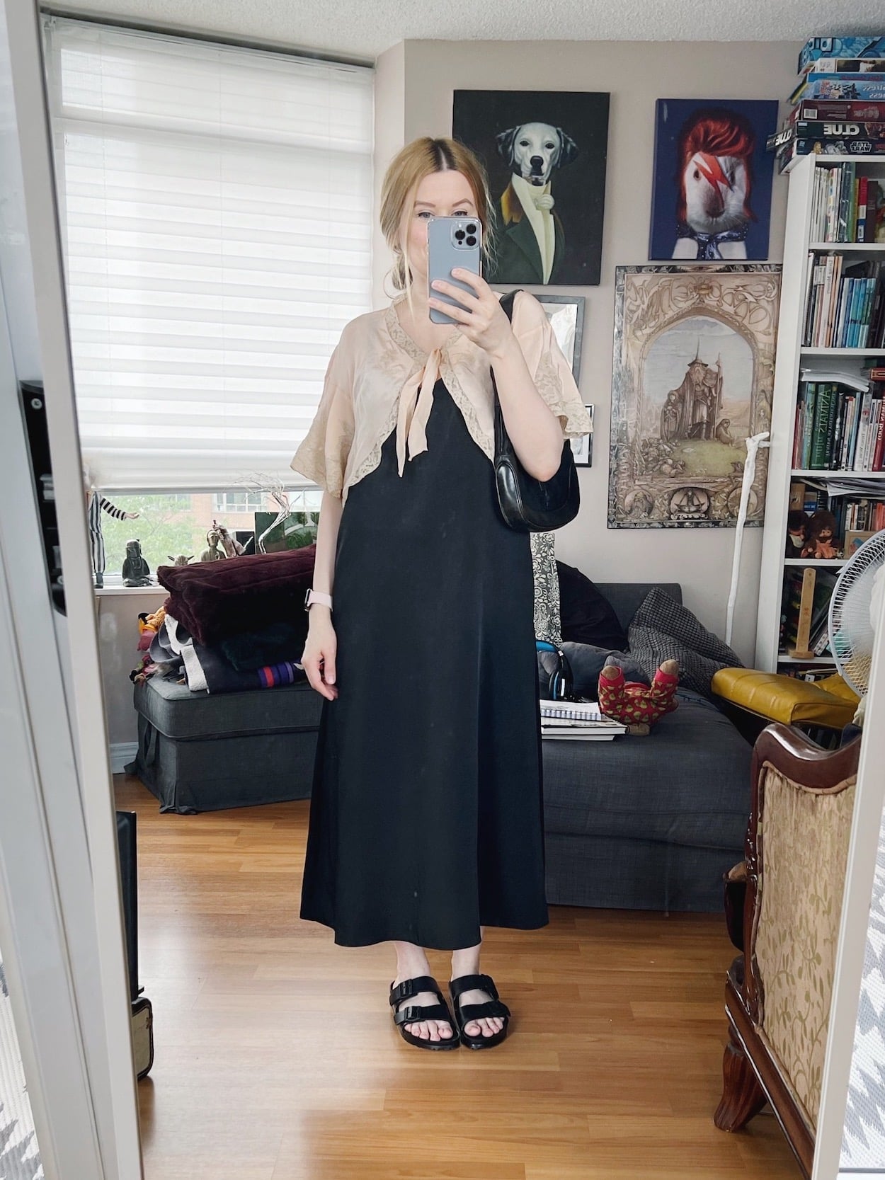 A blonde woman is wearing a black slip dress, a vintage bed jacket, Birkenstocks, and a Vintage Gucci bag.
