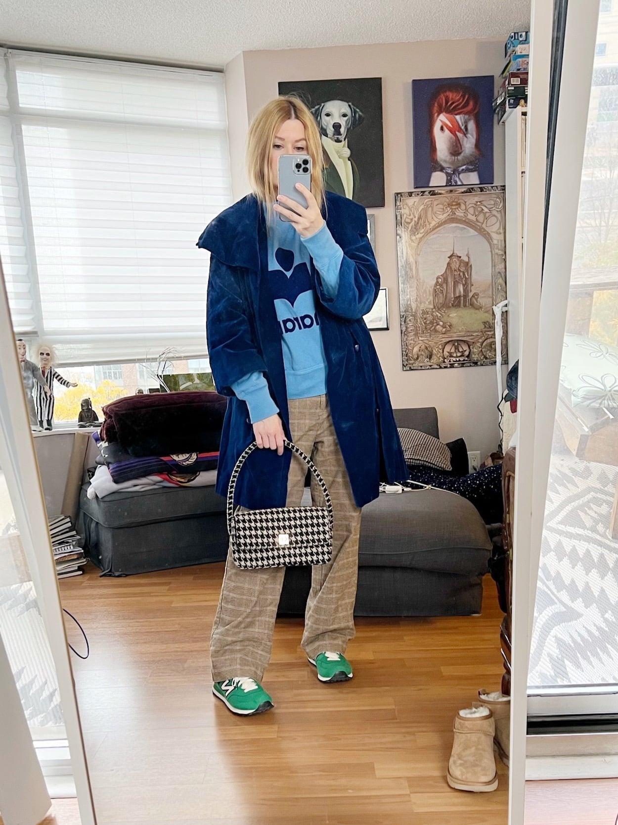 A blonde woman is wearing an Isabel Marant sweatshirt, checkered pants, blue vintage coat, green sneakers, and a houndstooth bag.