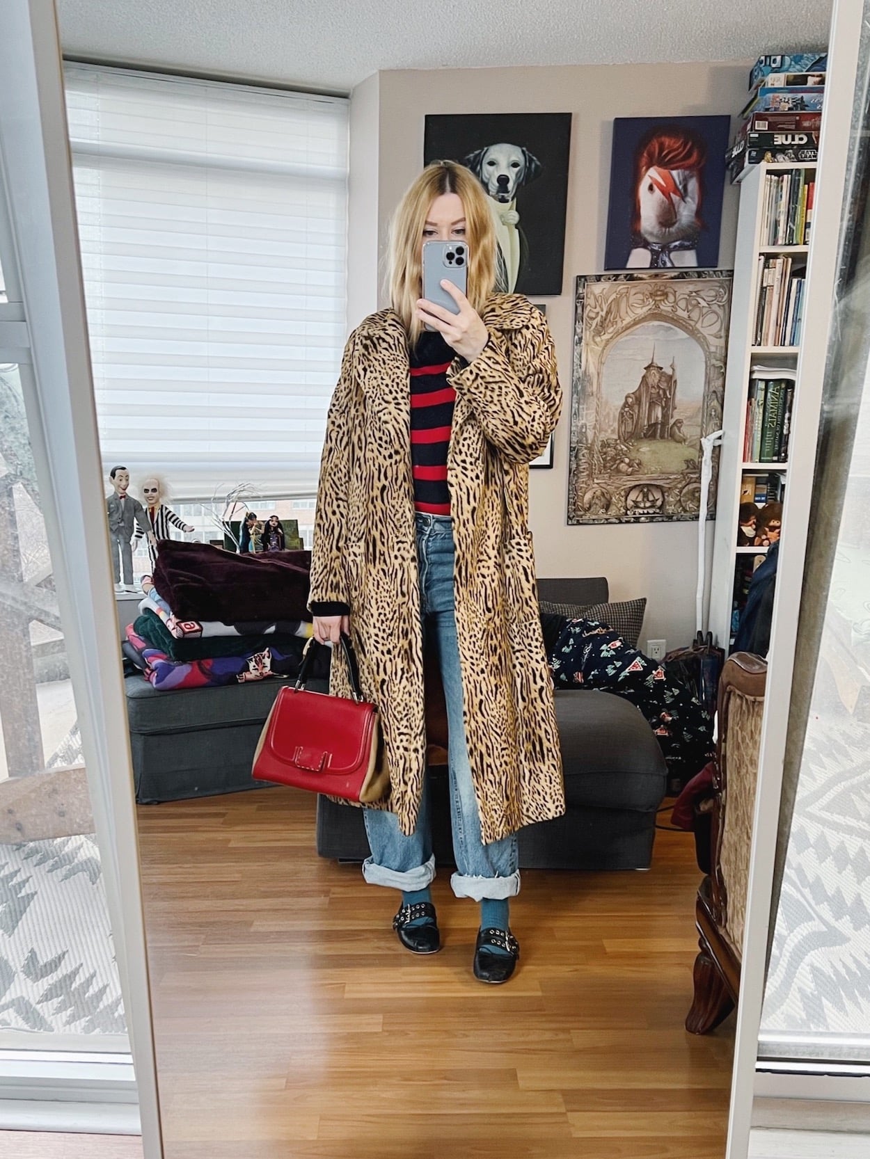 A blonde woman is wearing a striped sweater, jeans, ballets flats, a vintage animal print coat, and a vintage Fendi bag.