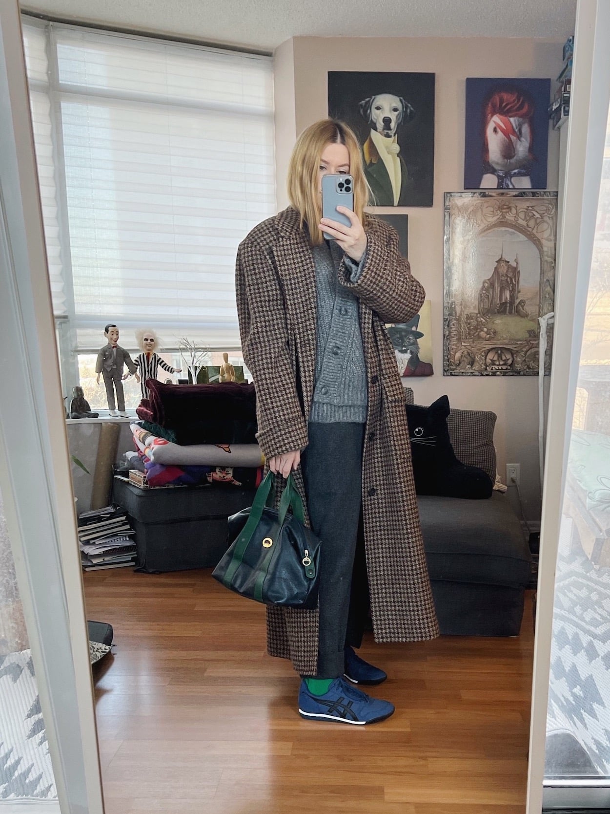 A blonde woman is wearing a grey cardigan, grey trousers, Onituska sneakers, a vintage Ralph Lauren bag, and vintage Longchamp bag.