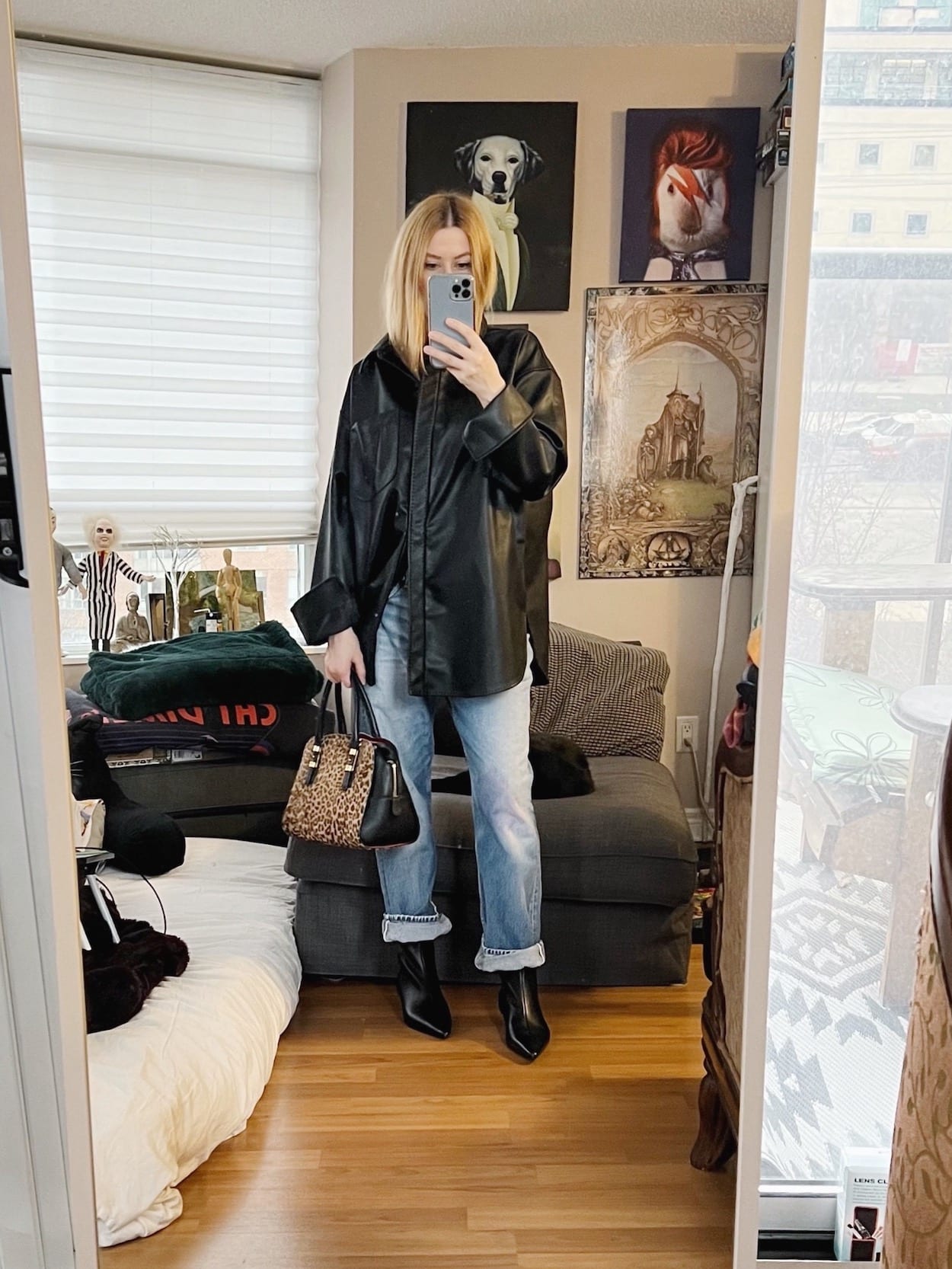 A blonde woman is wearing a leather shirt, vintage Levi's kitten-heeled boots, and a Ferragamo handbag.