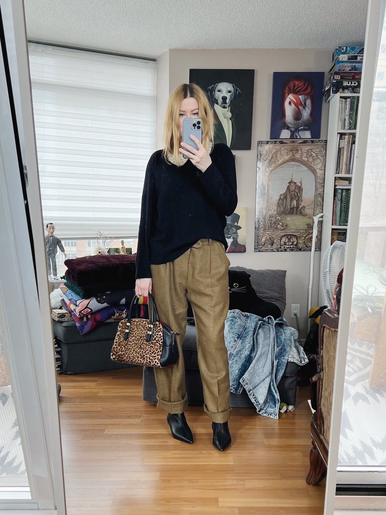 A blonde woman is wearing a cashmere sweater, vintage trousers, kitten heel boots, a vintage removable collar, and an animal print Ferragamo bag.