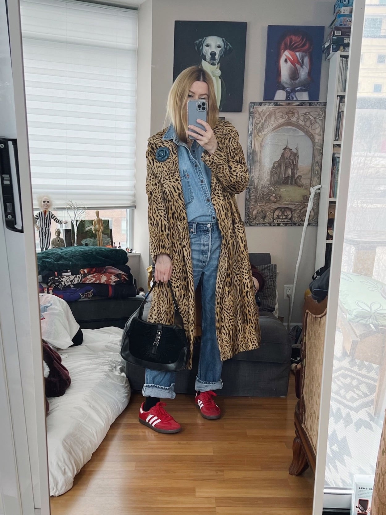 A blonde woman is wearing a denim shirt, vintage Levi's, a vintage animal print coat, red Adidas Sambas, and a vintage Gucci bag.