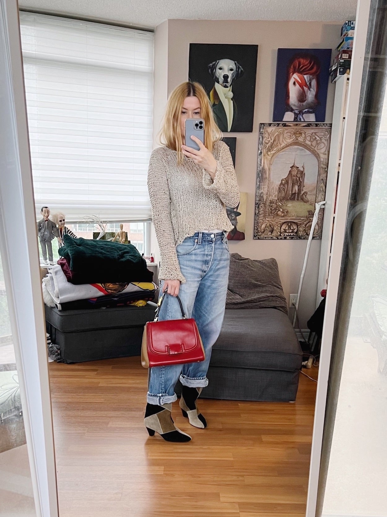 A blonde woman is wearing vintage levis, and open weave sweater, Isabel Marant boots, and a vintage Fendi bag.