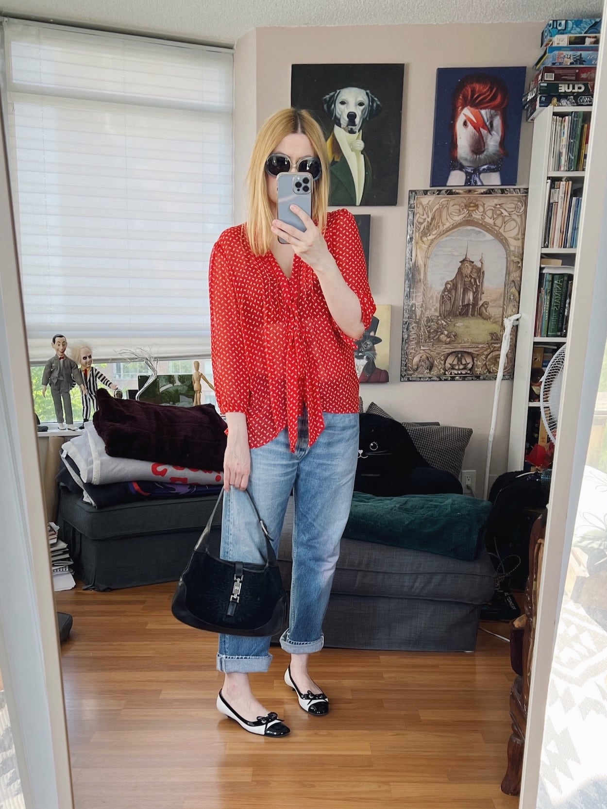 A blonde woman is wearing a red tie blouse, vintage Levi's, vintage sunnies, Chanel kitten heels, and a vintage Gucci handbag.