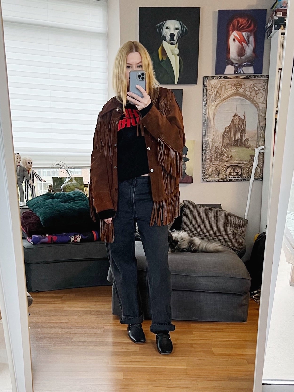 A blonde woman is wearing a Cure sweater, black Levi's, a vintage fringe jacket, and old Celine booties.