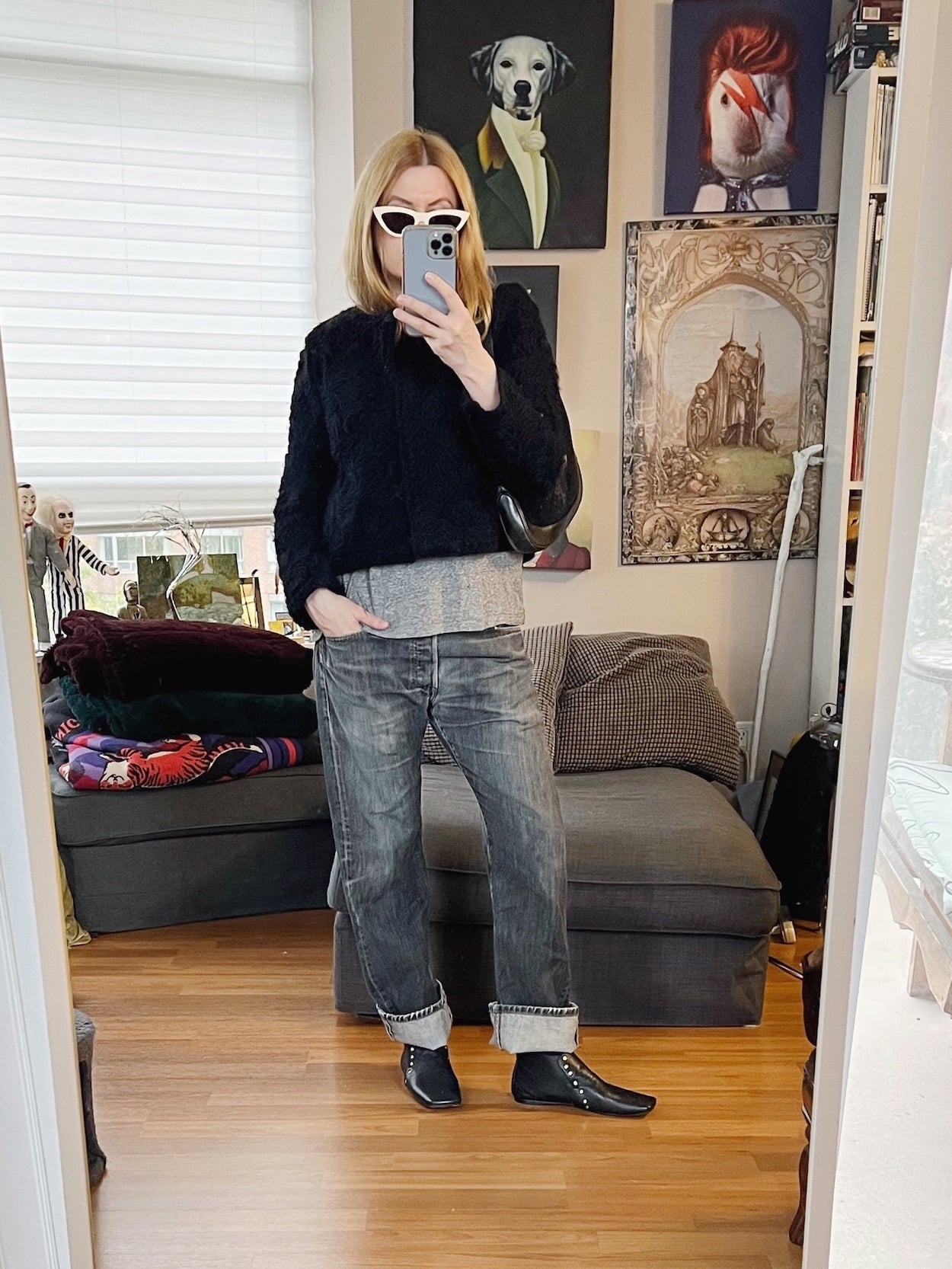 A blonde woman is wearing a grey t-shirt, vintage Levi's, a cropped black jacket, Celine boots, Celine sunglasses, and a vintage Gucci handbag.