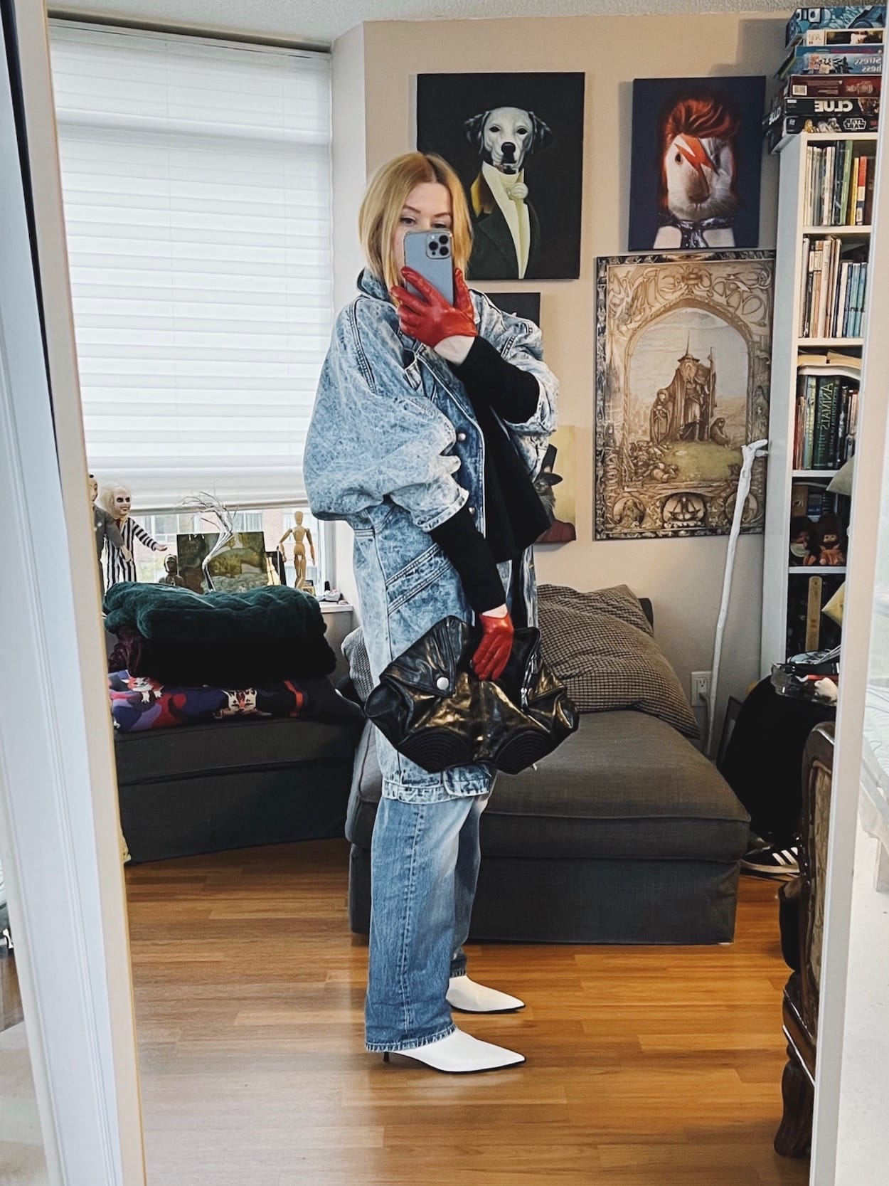 A blonde woman is wearing a black sweater, vintage Levi's an 80s denim jacket, white boots, red low scoop gloves, and is carrying an Alexander McQueen clutch.