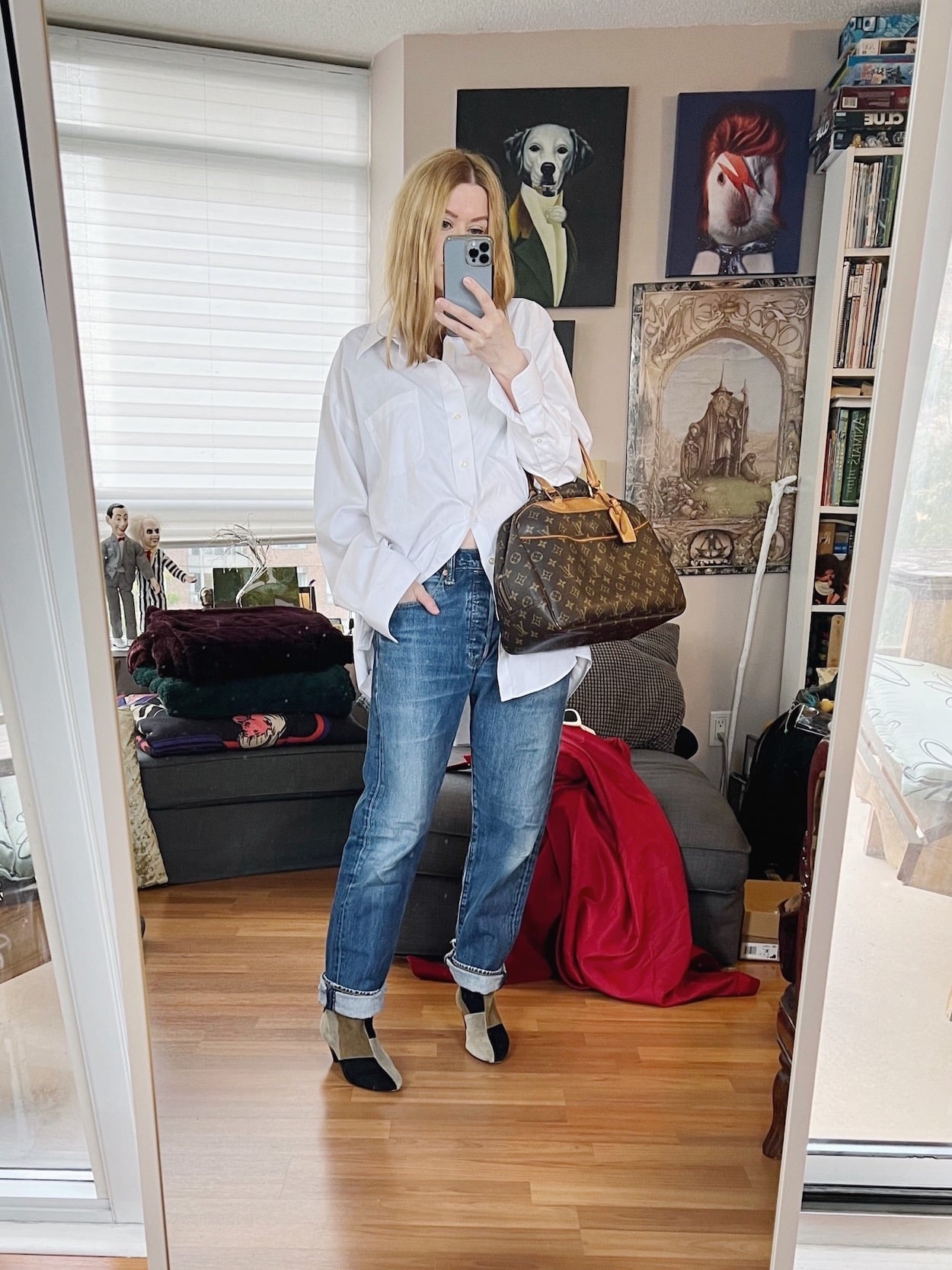 A blonde woman is wearing vintage Levis, and men's button up, Isabel Marant boots, and a vintage Louis Vuitton handbag.