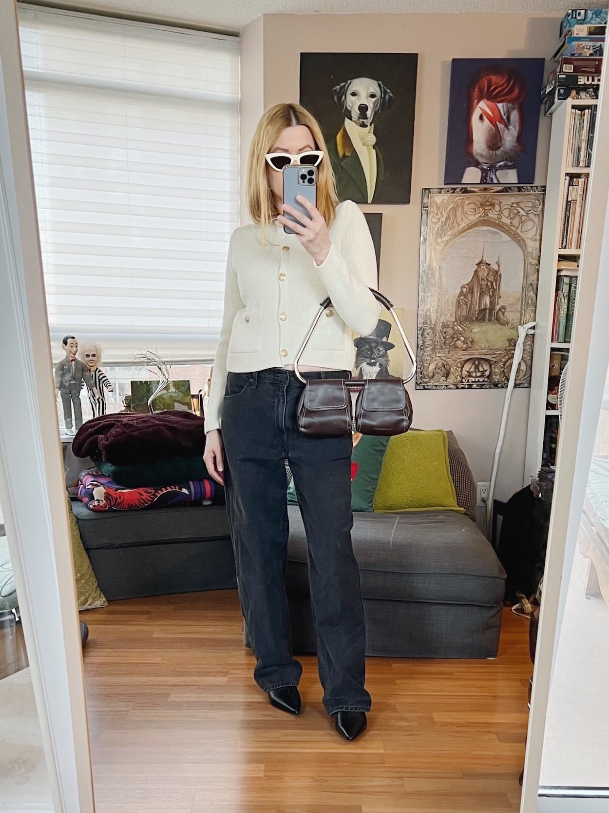 a blonde woman is wearing a cardigan, Levis, boots, Celine sunglasses, and a vintage handbag.