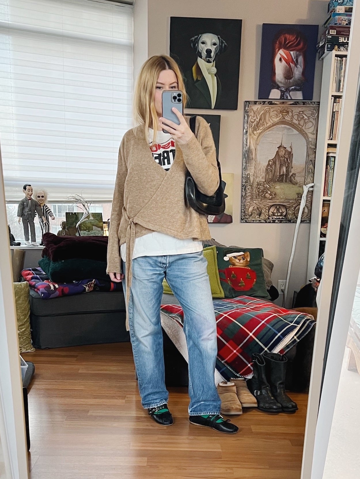 A blonde woman is wearing a Vision Streetwear t-shirt, wrap sweater, vintage Levi's, ballet flats, and a vintage Gucci bag.