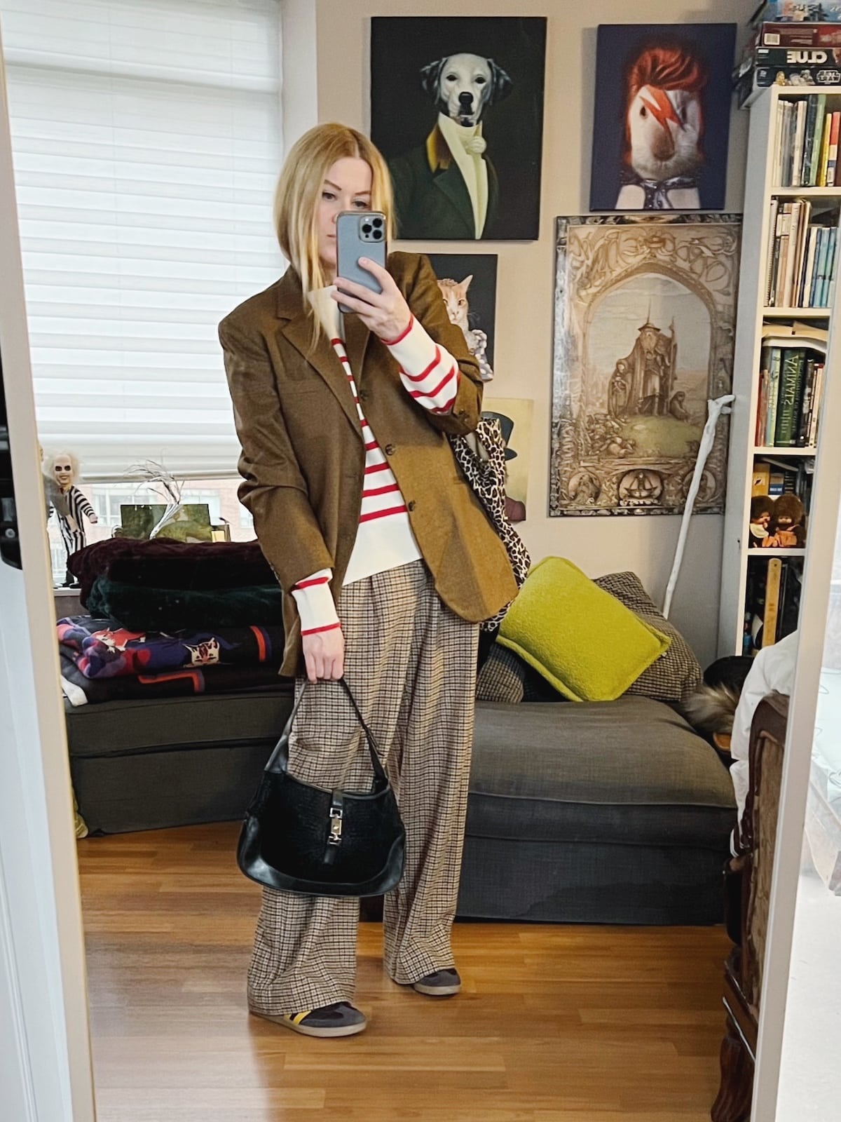 A blonde woman is wearing a striped sweater, trosuers, a vintage blazer, sneakers, and a vintage Gucci bag.
