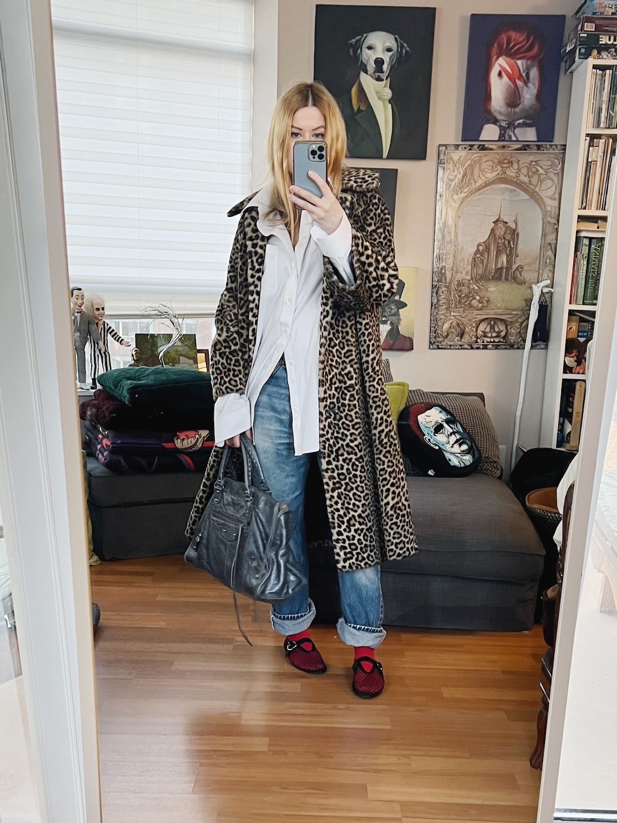 A blonde woman is wearing a white button up, vintage Levi's, mesh sandals, a vintage animal print coat, and a Balenciaga bag.