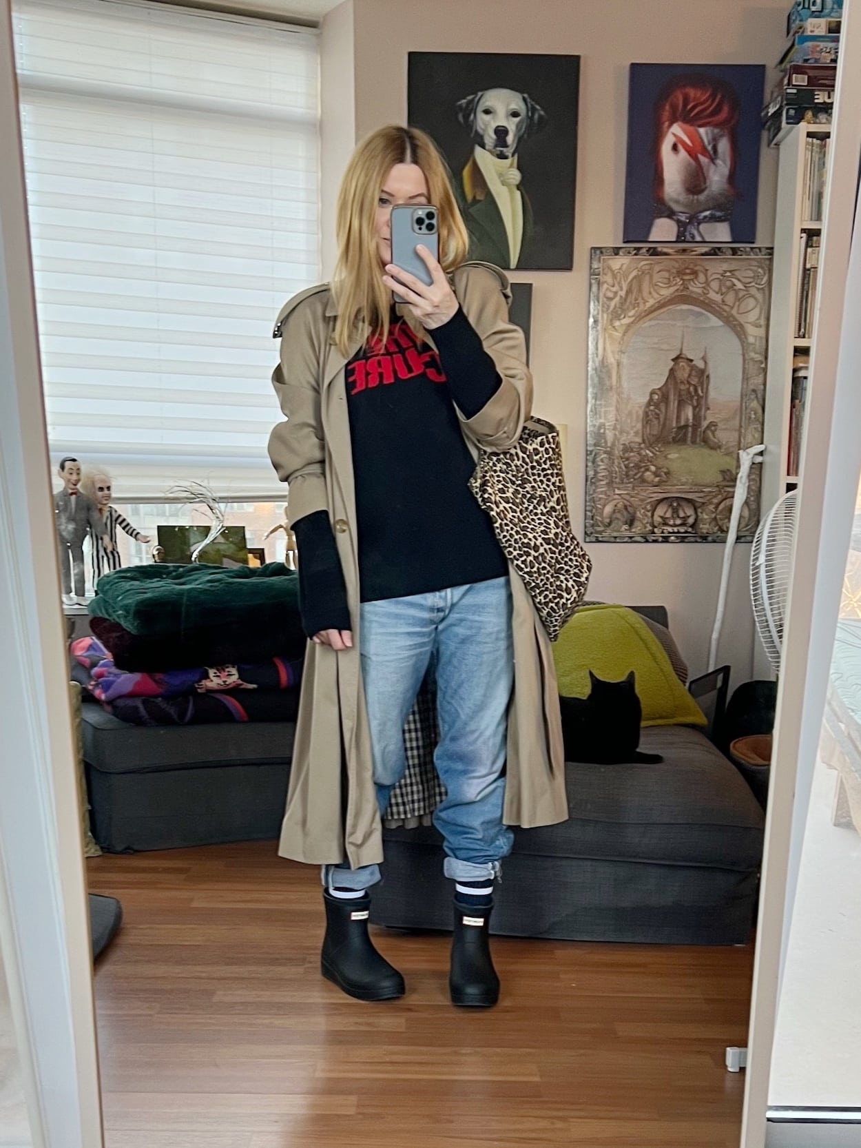 A blonde woman is wearing a Cure sweater, vintage Levis, a vintage trench, Hunter short boots, and an animal print tote.