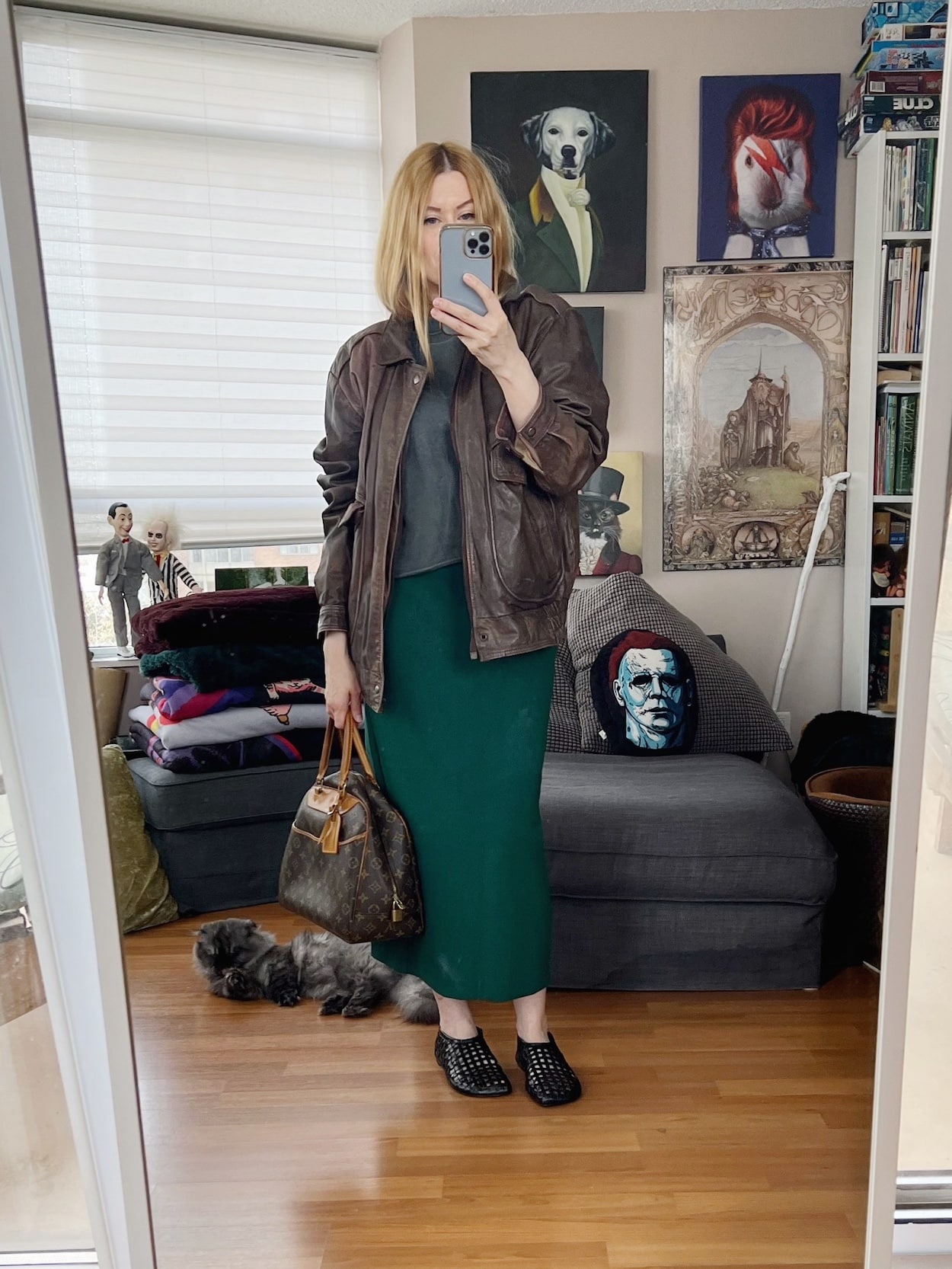 Sara of livelovesara is standing in front of a mirror taking a photo of her outfit. She is wearing a grey short sleeve sweatshirt, green column skirt, a vintage aviator, and a vintage bag.