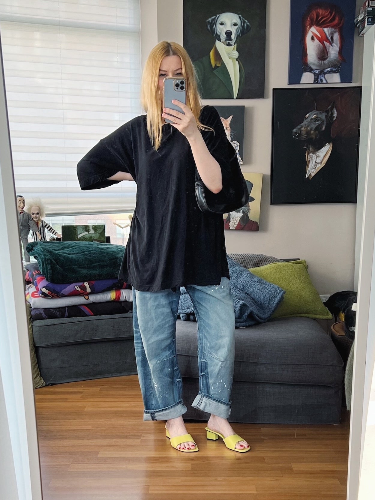 Sara of livelovesara is standing in front of a mirror taking a photo of her outfit. She is wearing an oversized black tee, Free People Moxie jeans, neon mules, and a vintage Gucci Jackie bag.