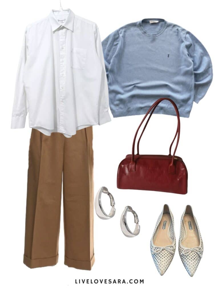 A photo of an outfit of a white button up over brown trousers, a blue sweater, white flats, a burgundy purse, and silver earrings.