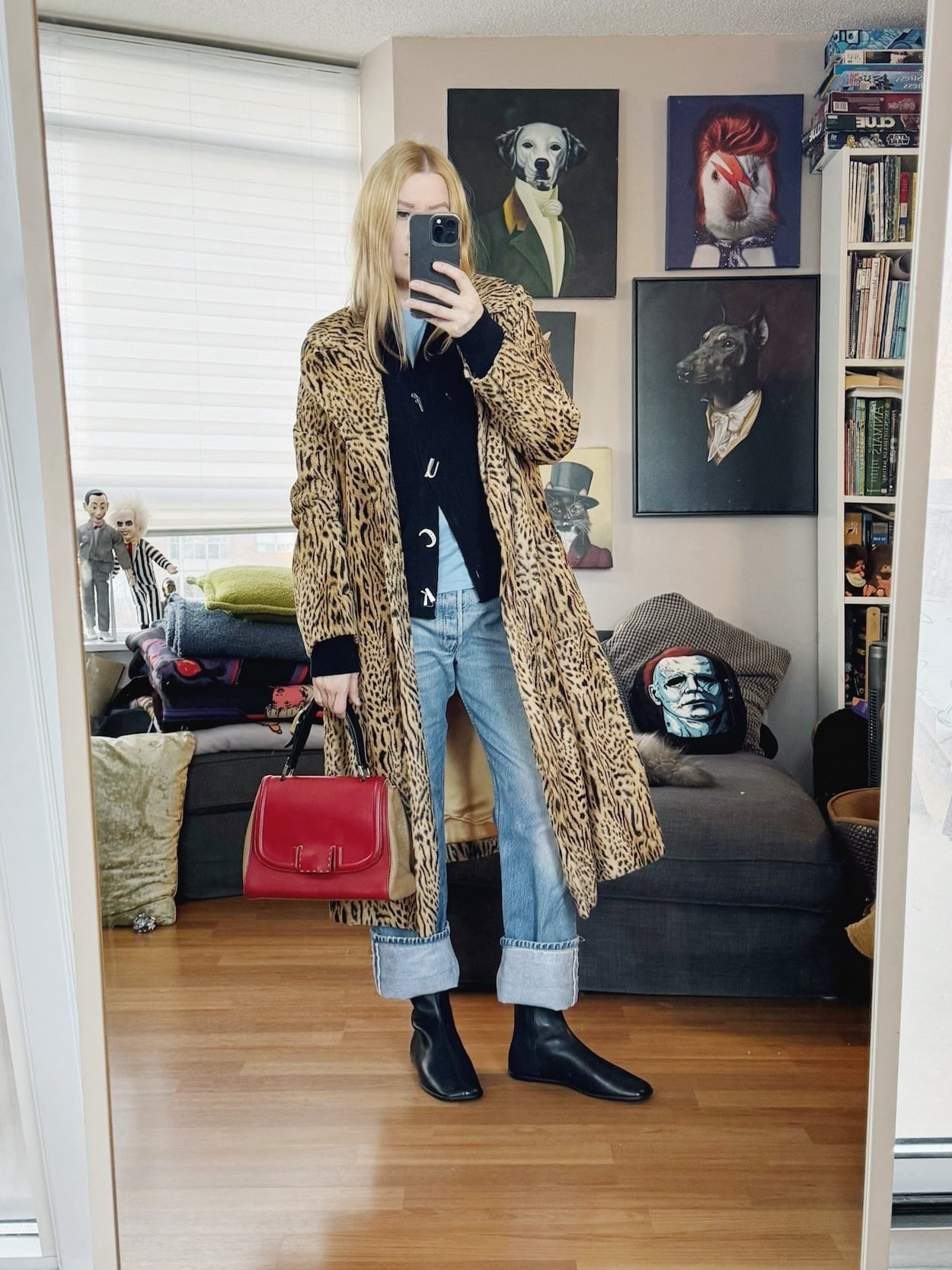Sara of livelovesara is standing in front of a mirror taking a photo of her outfit. She is wearing a blue tee, under a black cardigan, a vintage animal print coat, vintage Levi's, black boots, and a Fendi bag.