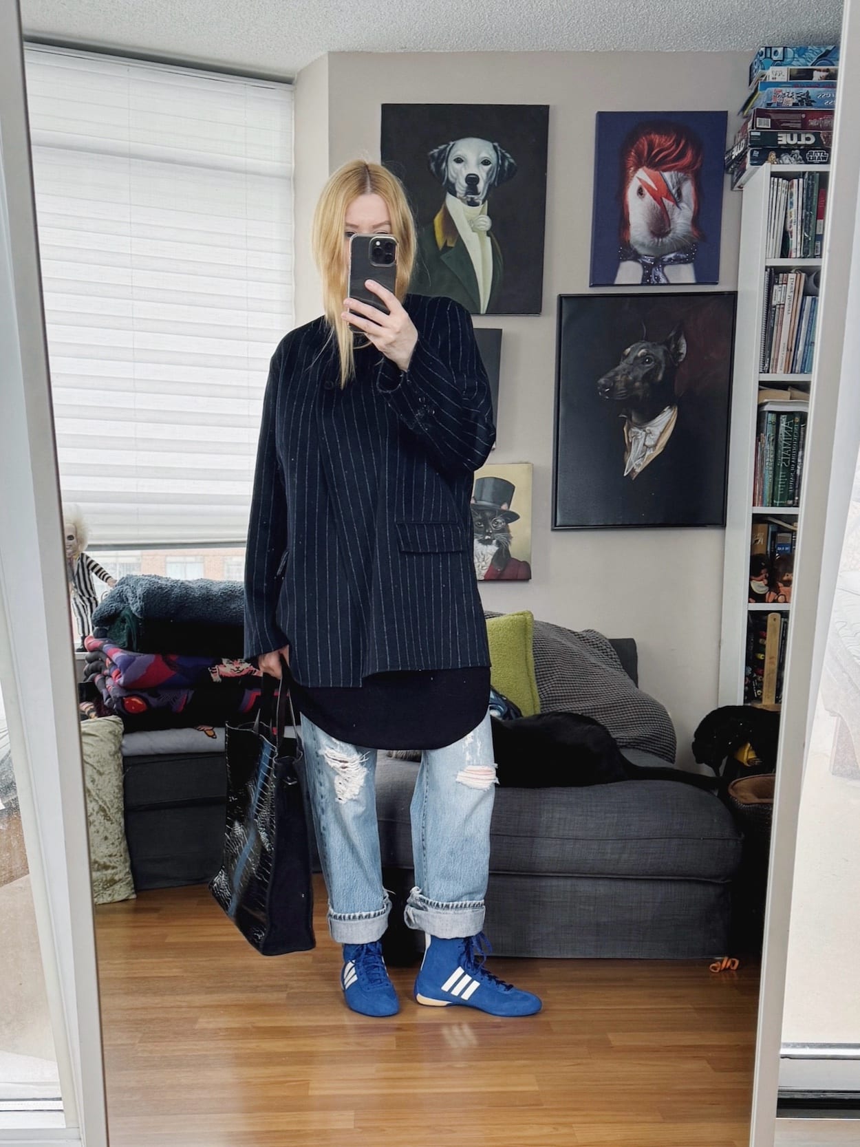 Sara of livelovesara is standing in front of a mirror taking a photo of her outfit. She is wearing an oversized blazer over a tunic, vintage jeans, Adidas Rasant, and a Dries Van Noten Tote.
