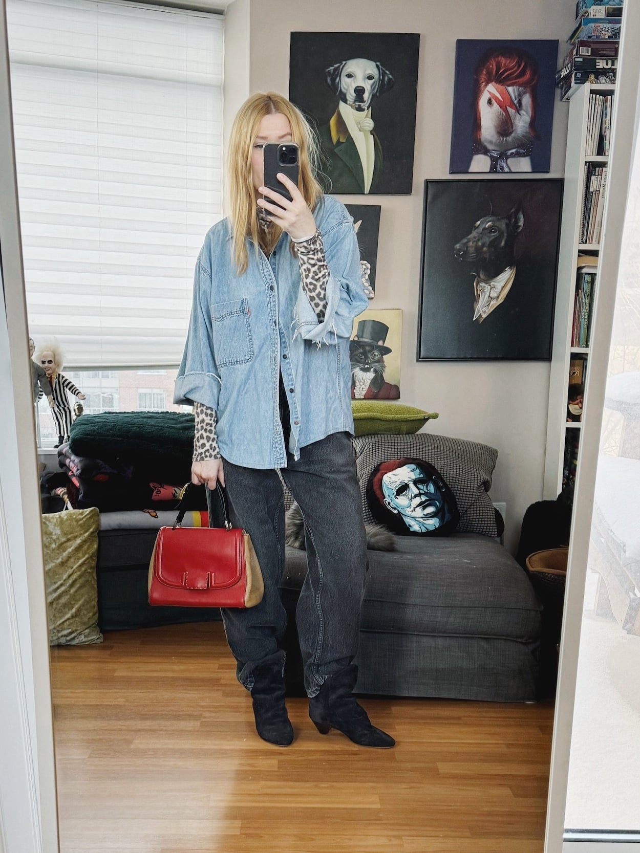 Sara of livelovesara is standing in front of a mirror taking a photo of her outfit. She is wearing an animal print turtleneck under a denim shirt, black vintage Levis, Isabel Marant boots, and a Fendi Silvana bag.