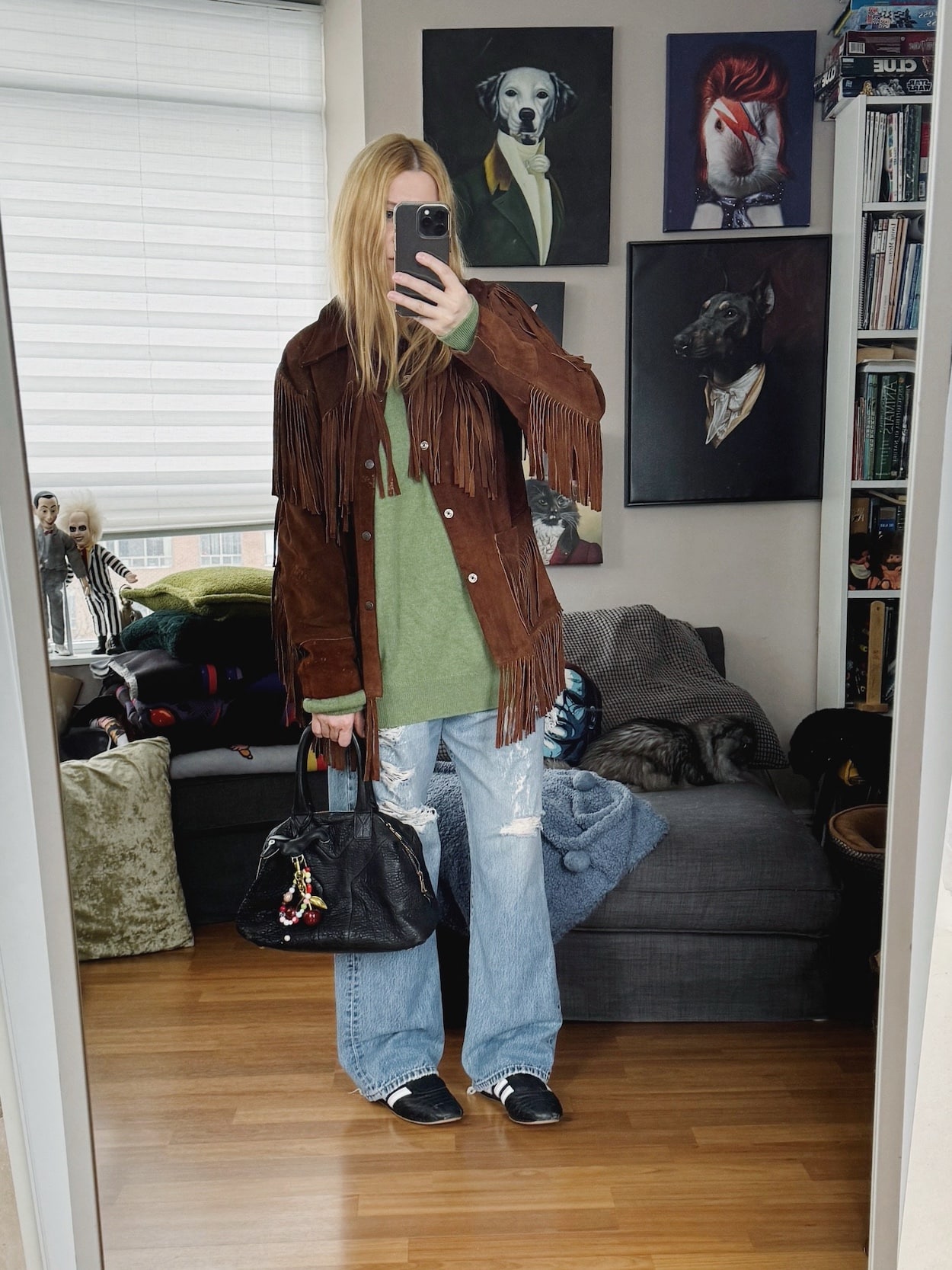 Sara of livelovesara is standing in front of a mirror taking a photo of her outfit. She is wearing a green cashmere sweater under a vintage fringe jacket, vintage Levi's. Adidas Taekwondo, and a YSL easy bag.