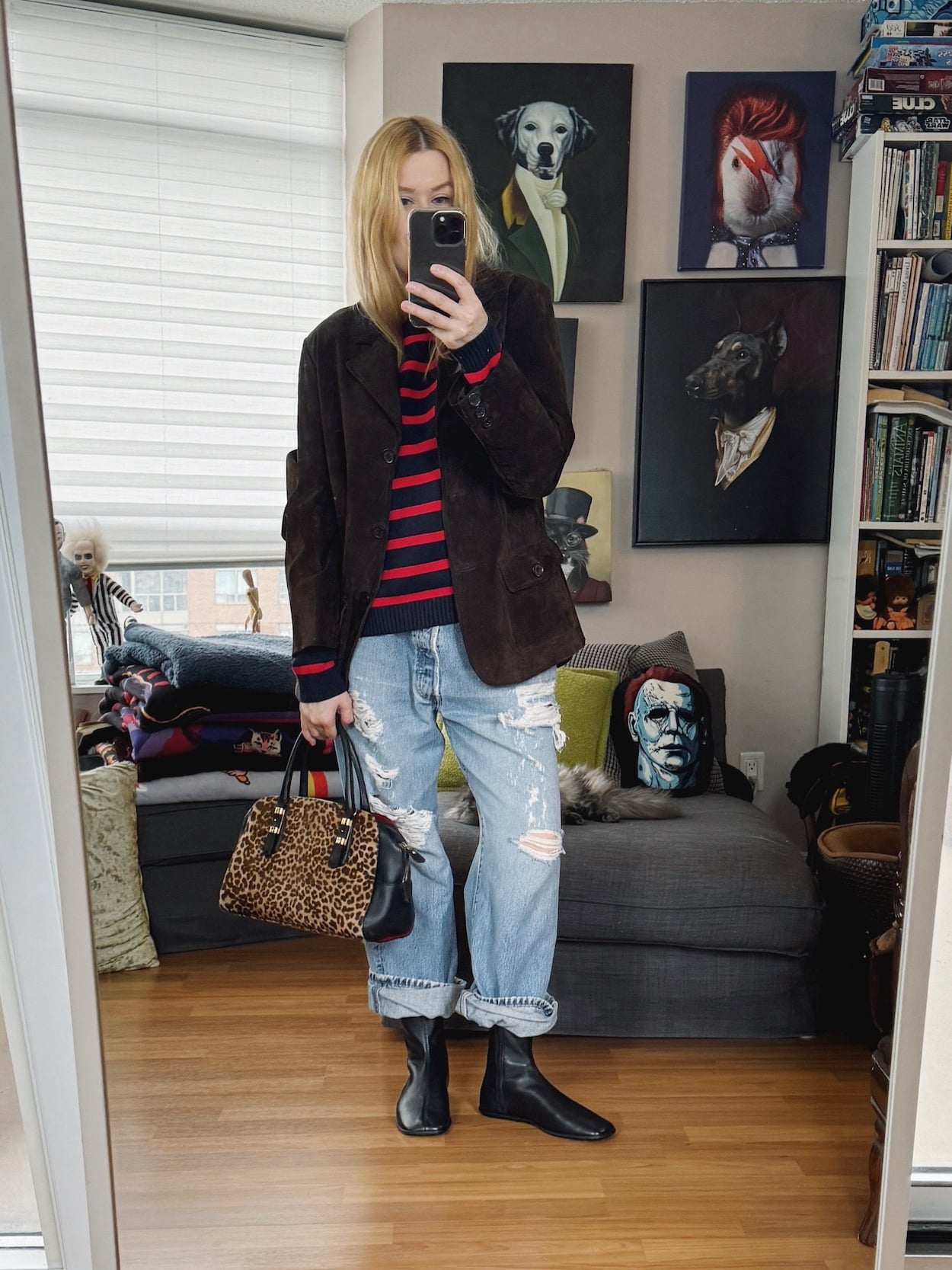 Sara of livelovesara is standing in front of a mirror taking a photo of her outfit. She is wearing a navy and red striped sweater under a brown suede blazer, vintage Levis with distressing, black boots, and an animal print bag.