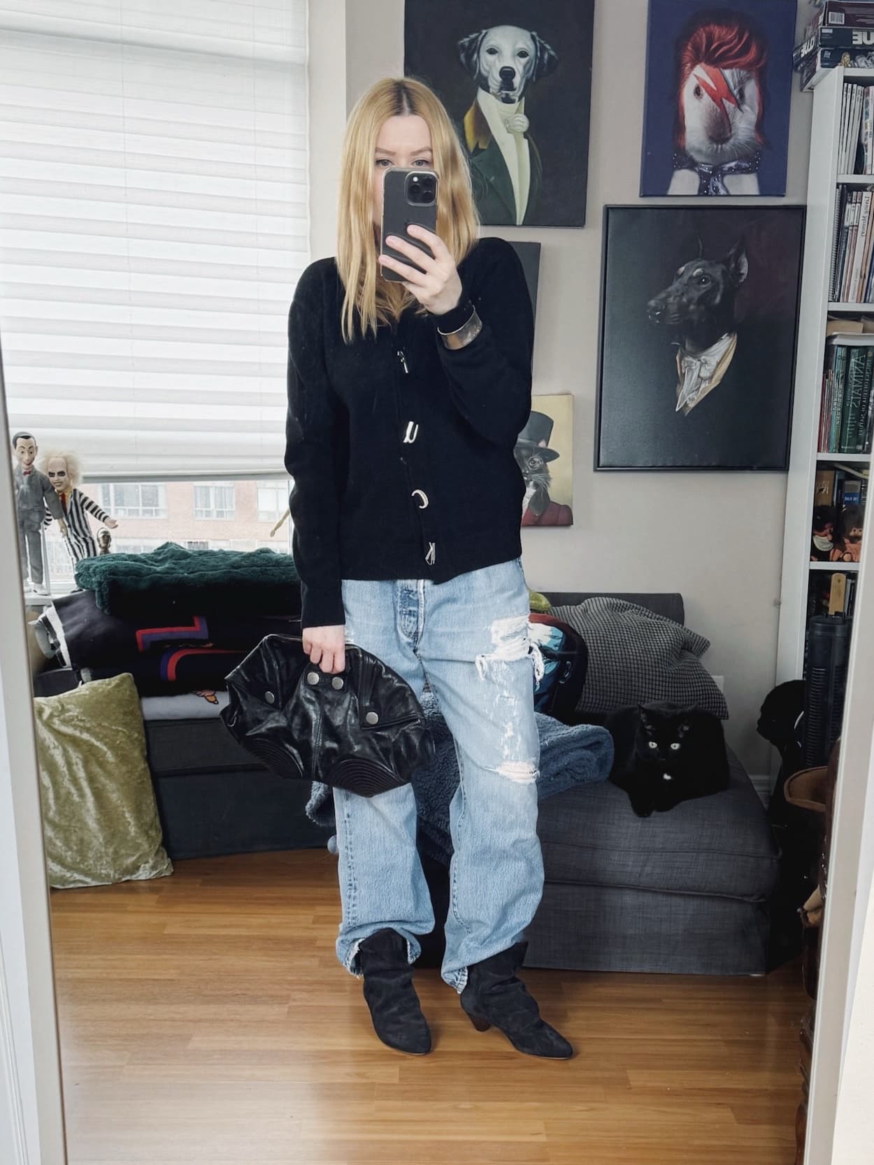 Sara of livelovesara is standing in front of a mirror taking a photo of her outfit. She is wearing an Fuck buttons sweater, vintage distressed Levi's, Isabel Marant boots, and an Alexander McQueen clutch.