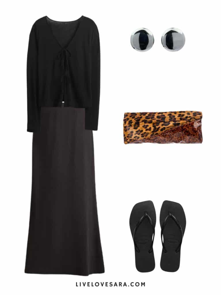 A photo of an outfit of a black linen tie front top, a black maxi skirt, flip flips, round earrings, and an animal print clutch.