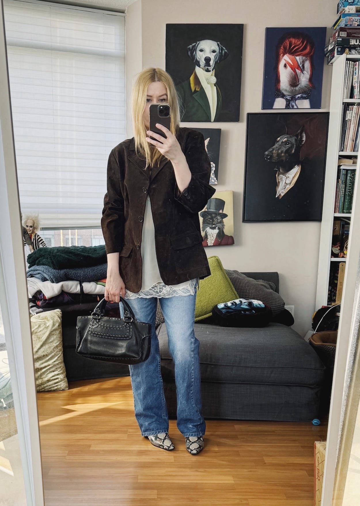 Sara of livelovesara is standing in front of a mirror taking a photo of her outfit. She is wearing a camisole under a vintage suede blazer, vintage Levis, snake print boots, and a vintage Celine Boogie bag.