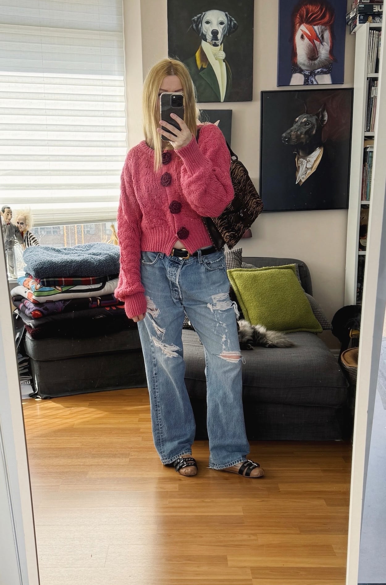 Sara of livelovesara is standing in front of a mirror taking a photo of her outfit. She is wearing a pink cardigan with distresses Levis, pink Miu Miu flats, and an animal print bag.