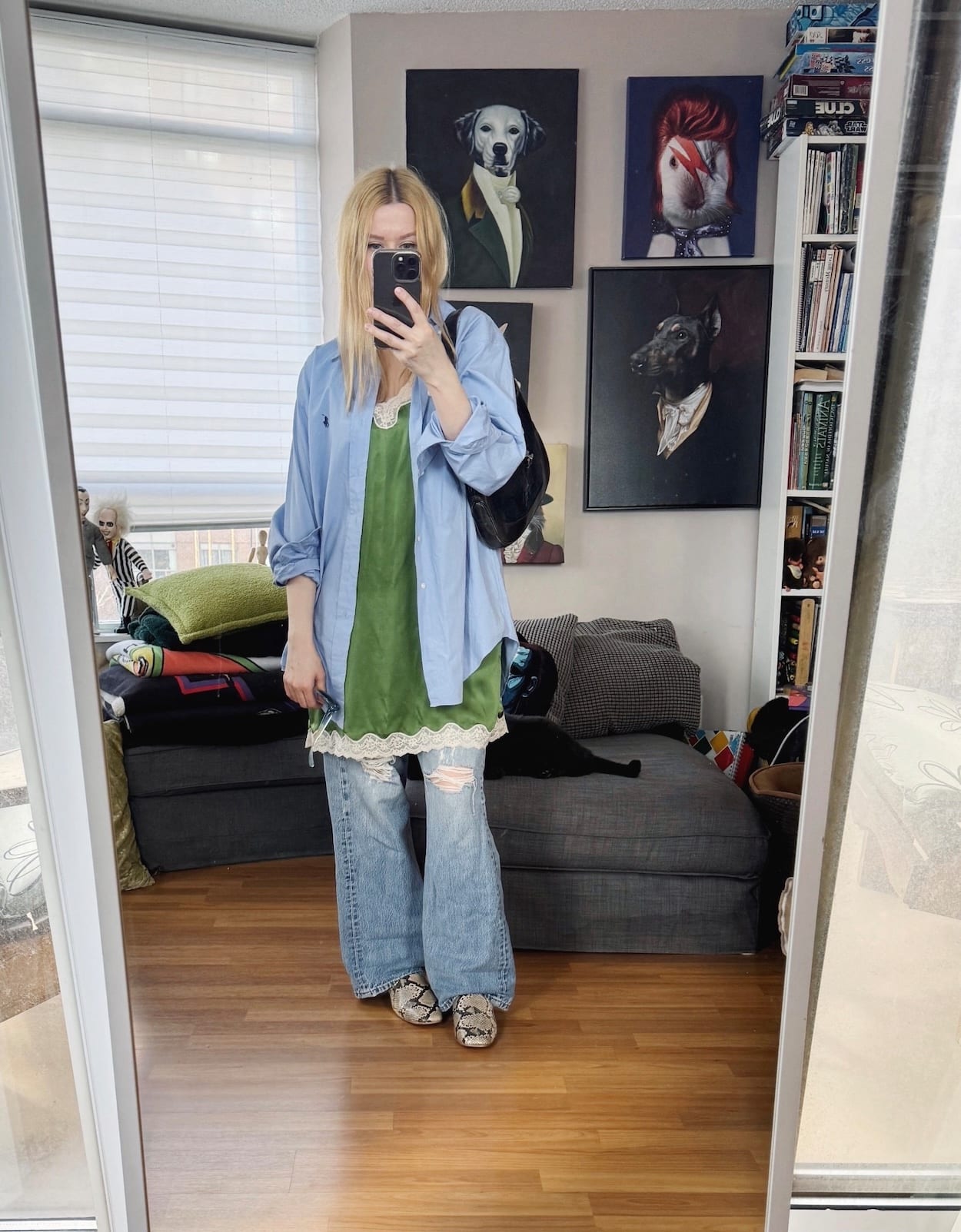 Sara of livelovesara is standing in front of a mirror taking a photo of her outfit. She is wearing a green dress over vintage Levis, a blue button up, snake print mules, and a vintage Gucci Jackie bag.