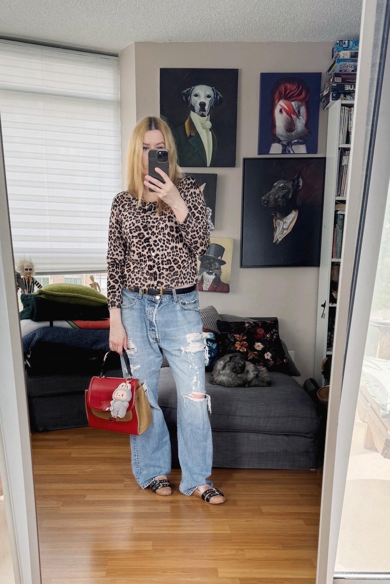 Sara of livelovesara is standing in front of a mirror taking a photo of her outfit. She is wearing an animal print cardigan with vintage levis, miu miu flats, and a Fendi bag with a labubu.